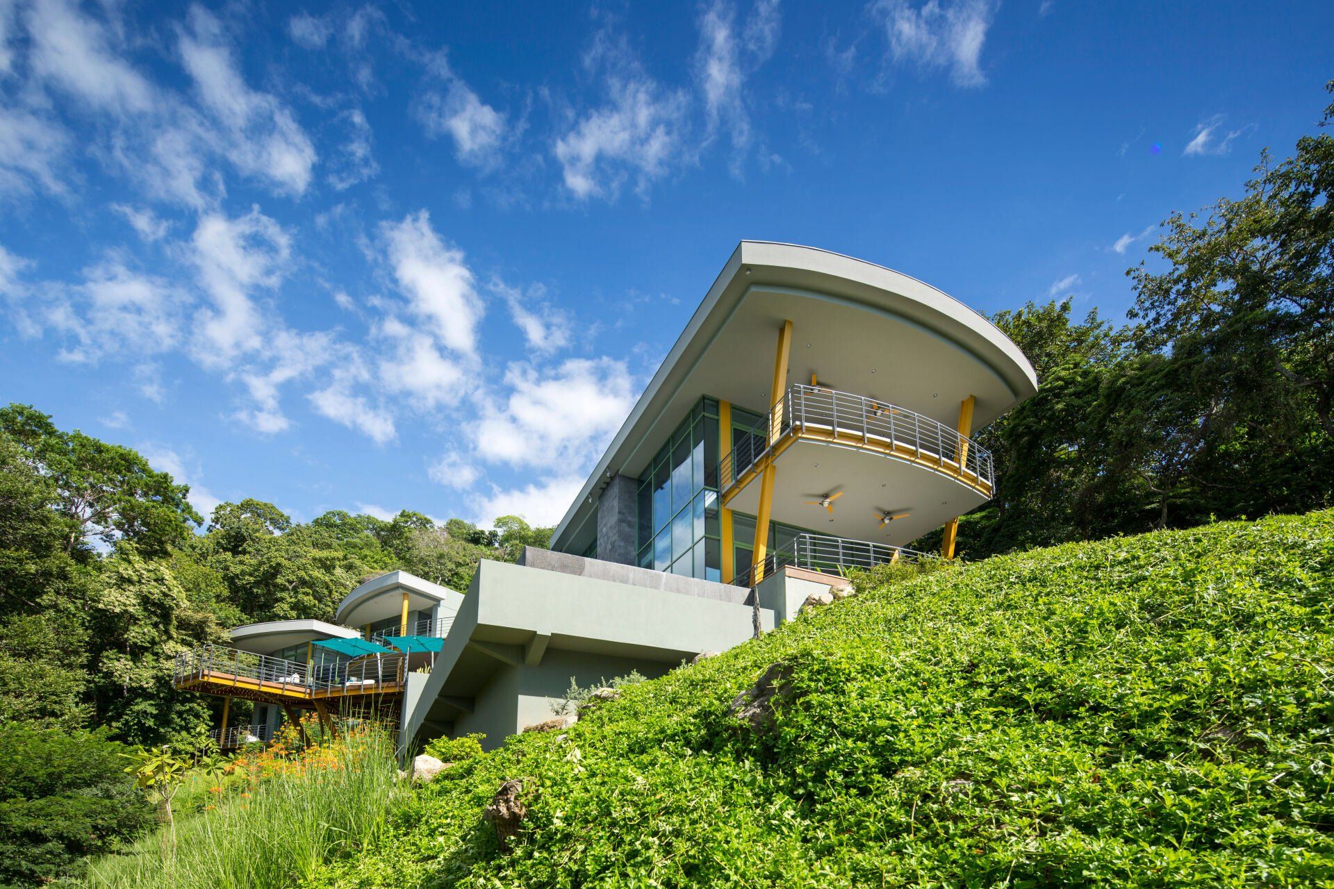a modern house is sitting on top of a hill surrounded by trees .