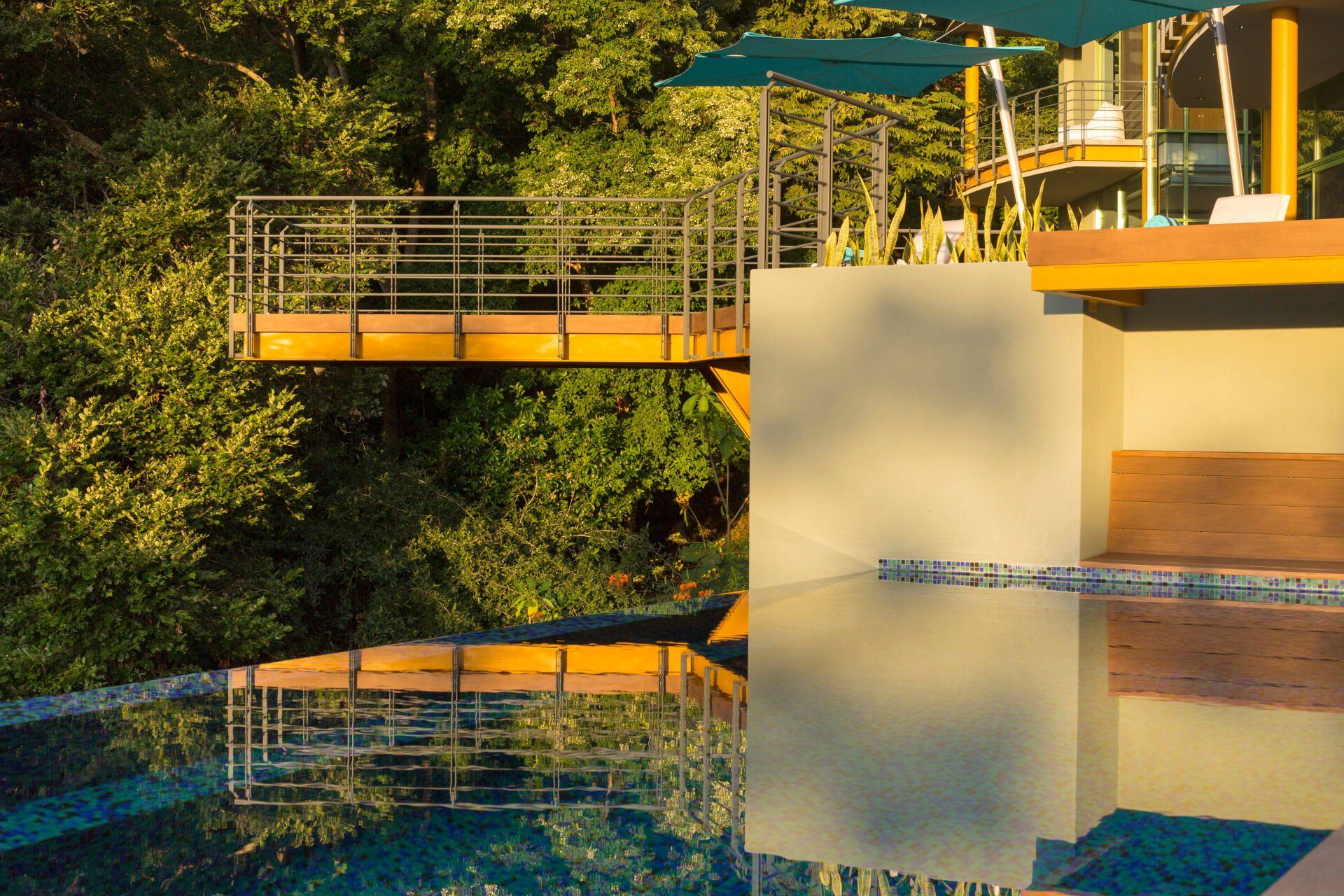 a swimming pool with a bridge over it and trees in the background