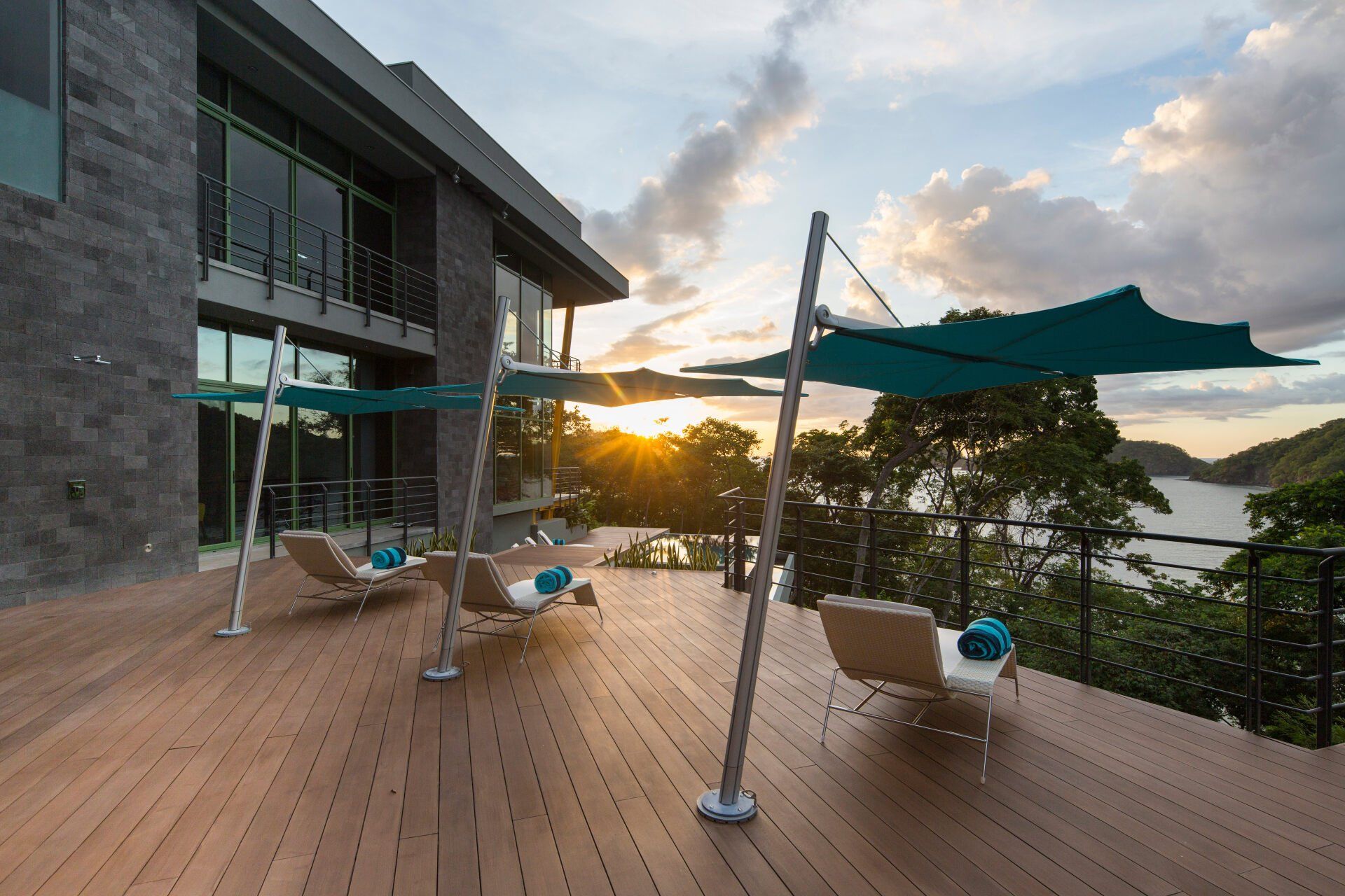 a deck with chairs and umbrellas in front of a house