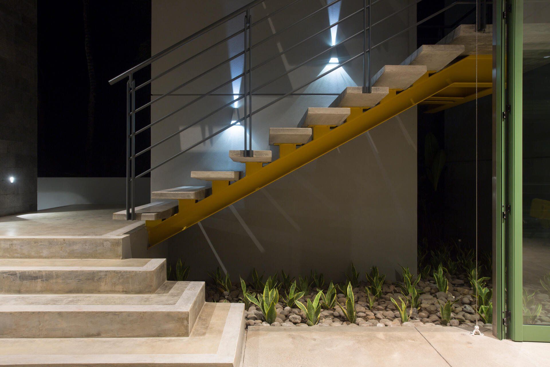a set of stairs with a yellow railing and a green door