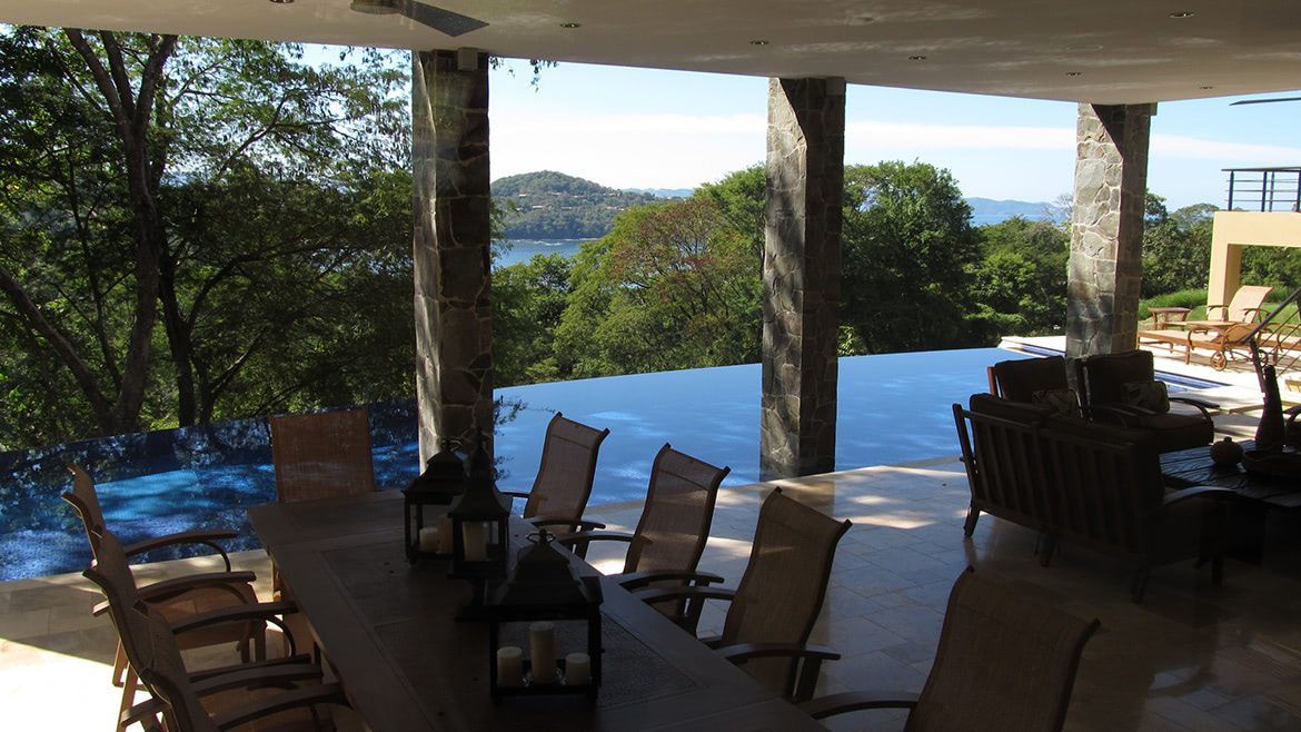 a patio with a table and chairs overlooking a swimming pool