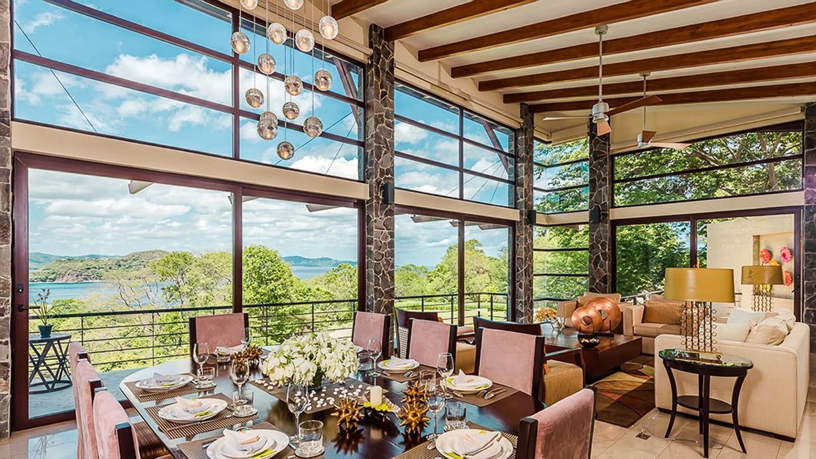 a large dining room with a table and chairs and a view of the ocean .