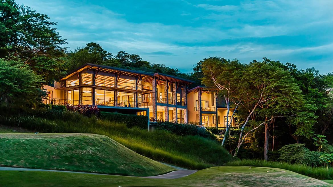 a large house is lit up at night in the middle of a forest .