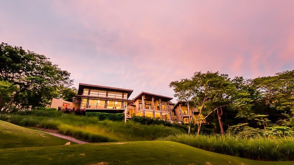 a large house is sitting on top of a hill surrounded by trees .