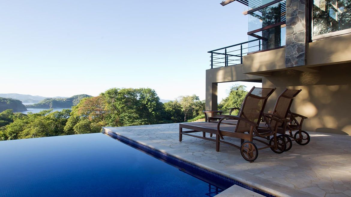 a swimming pool with a view of a lake and a house in the background .