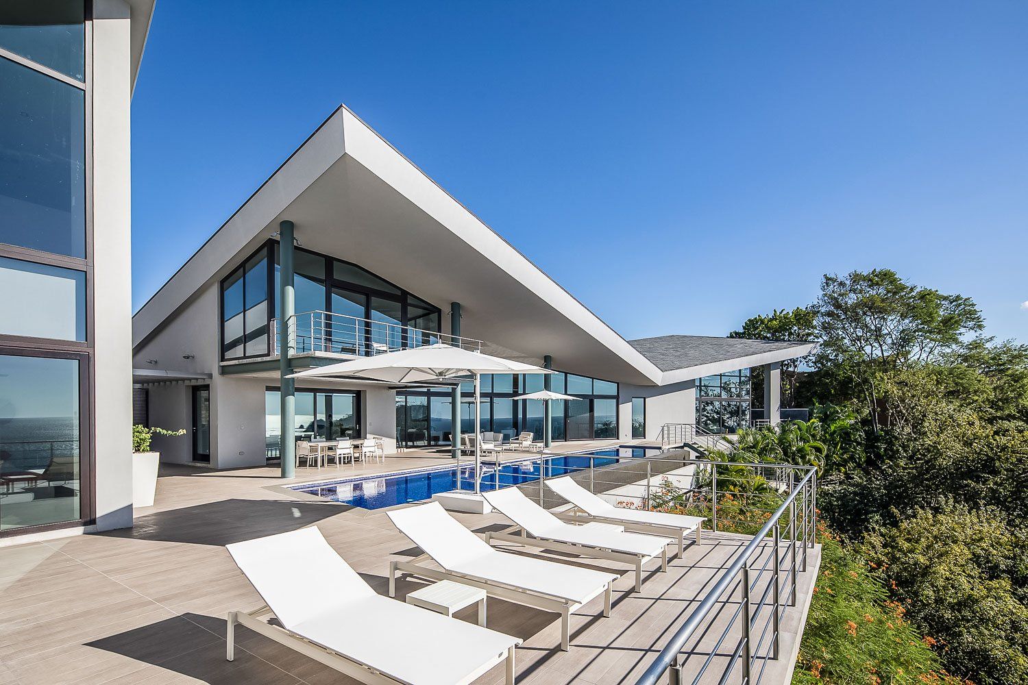 a large house with a swimming pool and lounge chairs in front of it .