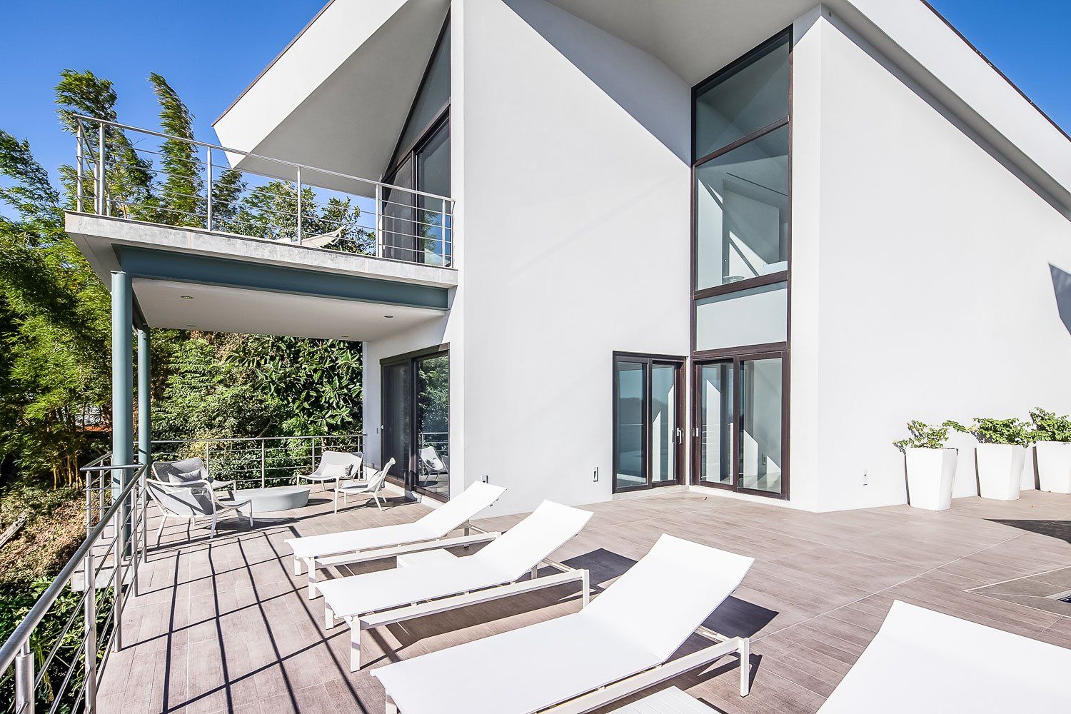 a large white house with a balcony and lounge chairs on it