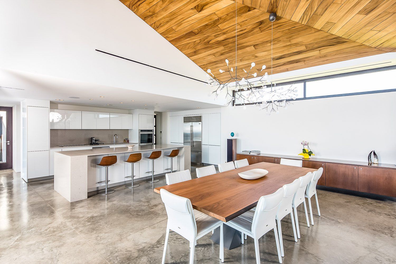 a dining room with a long wooden table and white chairs .