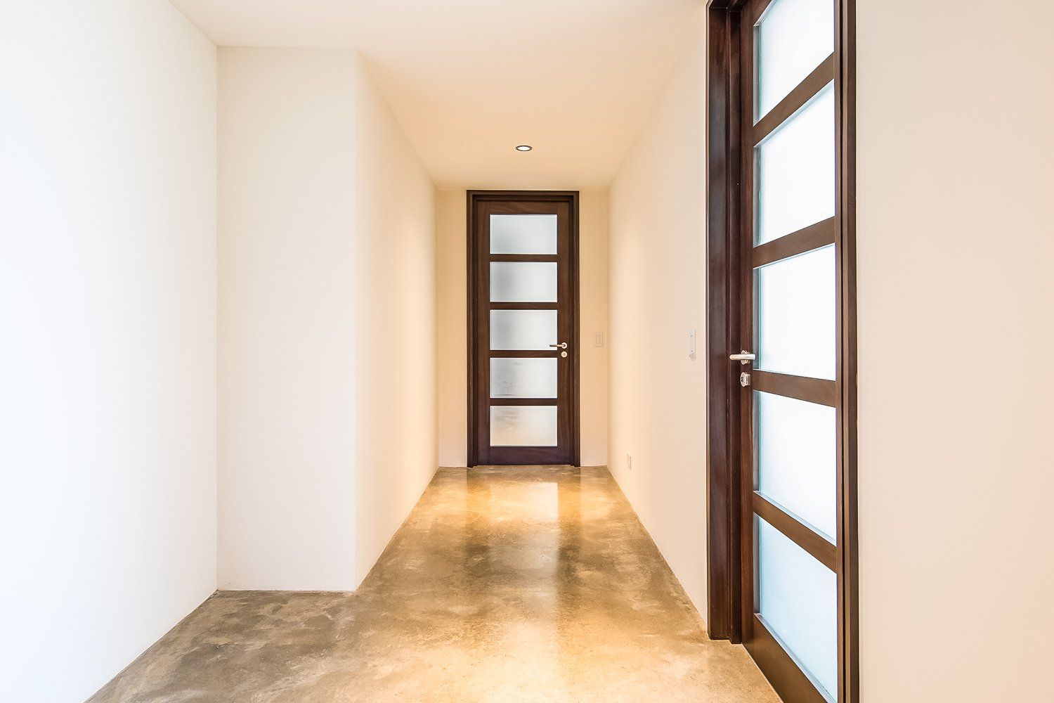 an empty hallway with a wooden door and a glass door .