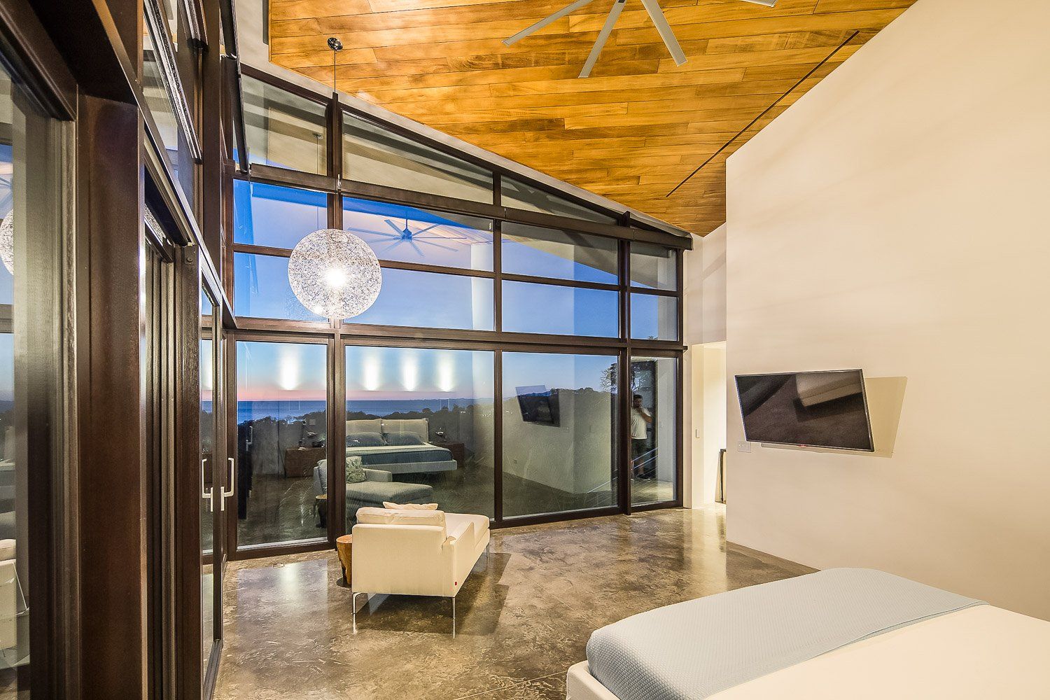 a bedroom with a lot of windows and a ceiling fan .