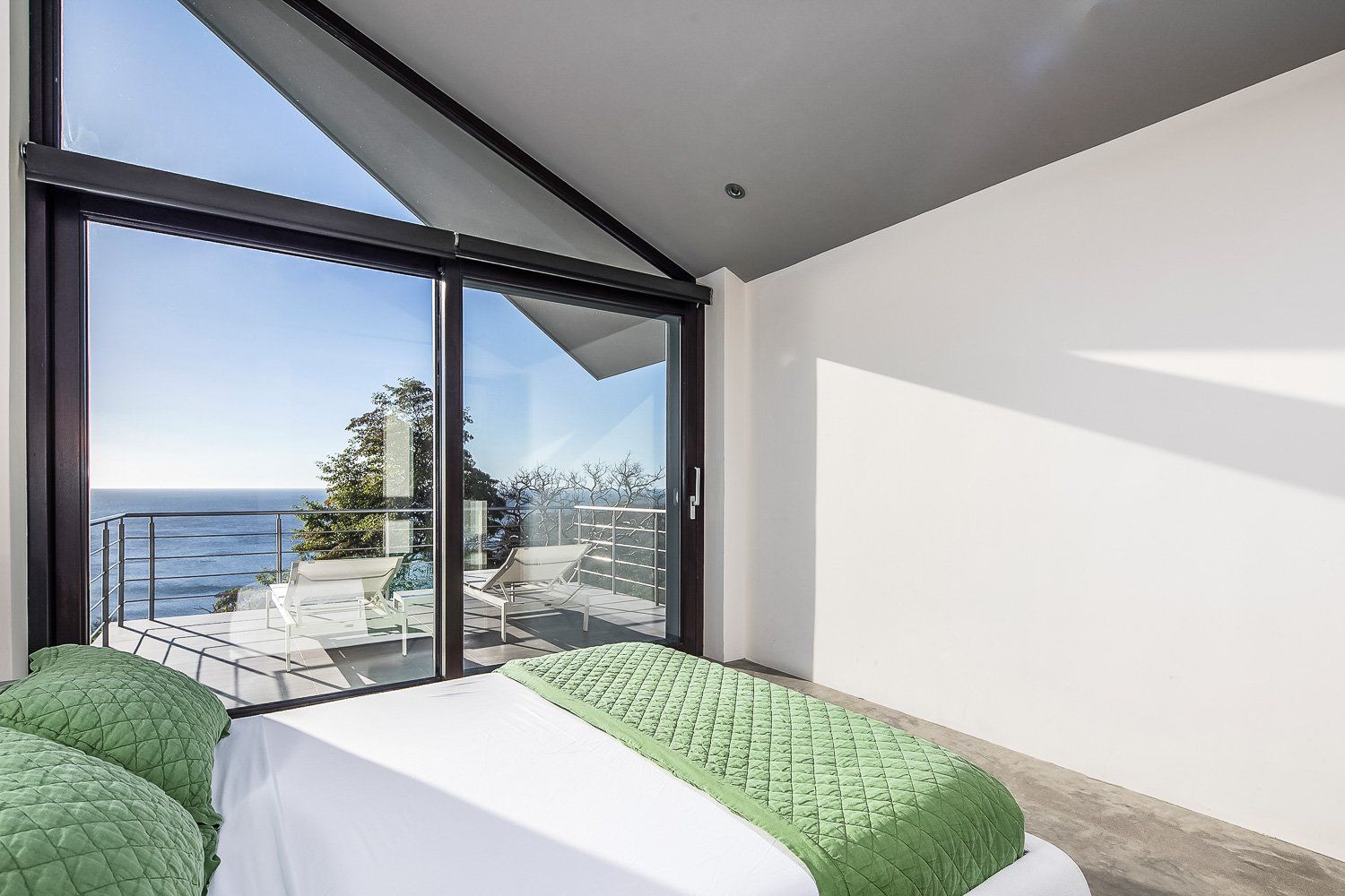 a bedroom with a bed and a balcony overlooking the ocean .