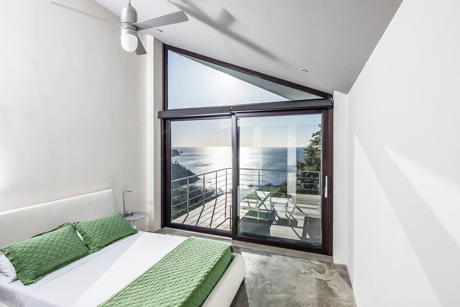 a bedroom with a bed and a balcony overlooking the ocean .