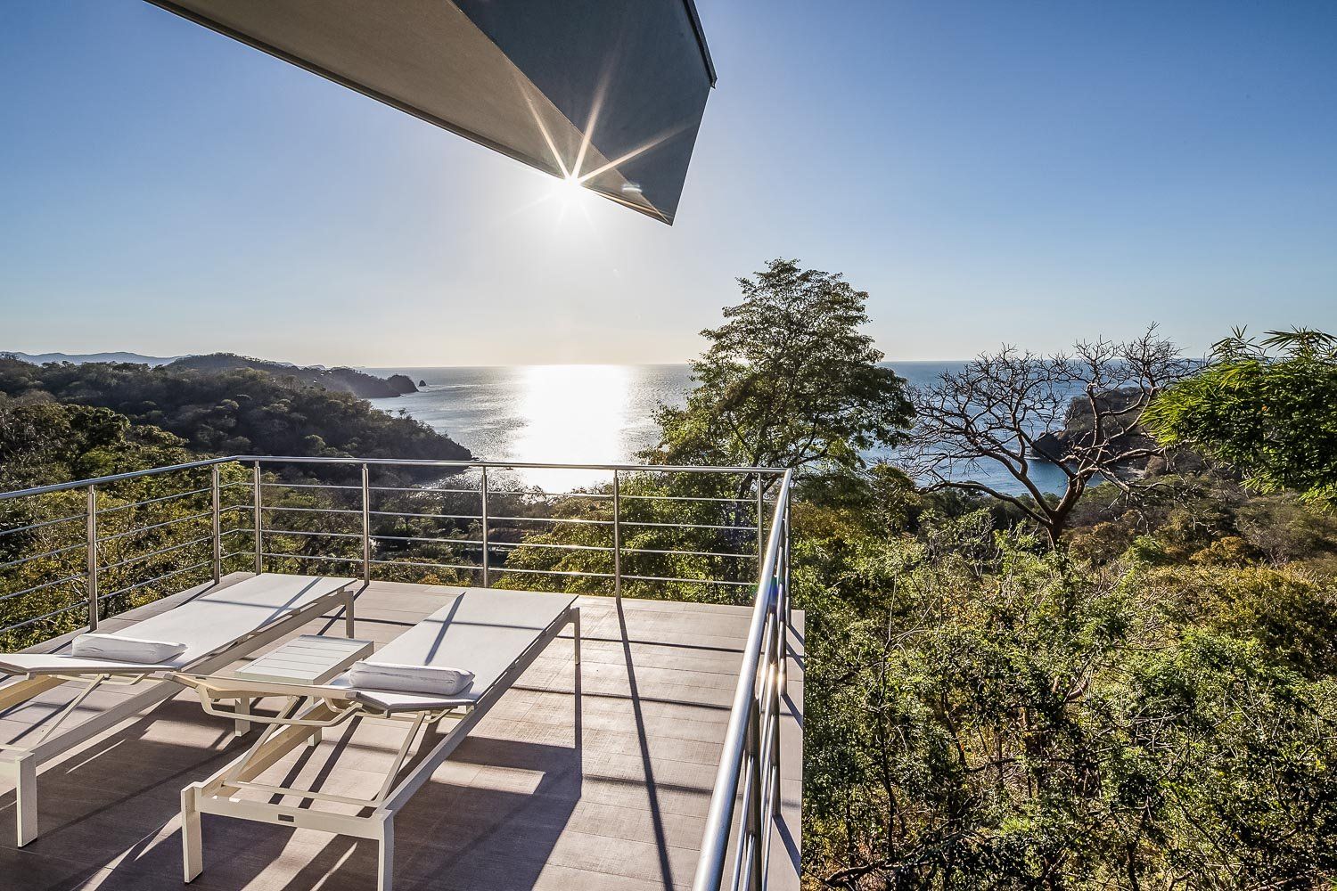 a view of the ocean from a balcony with lounge chairs