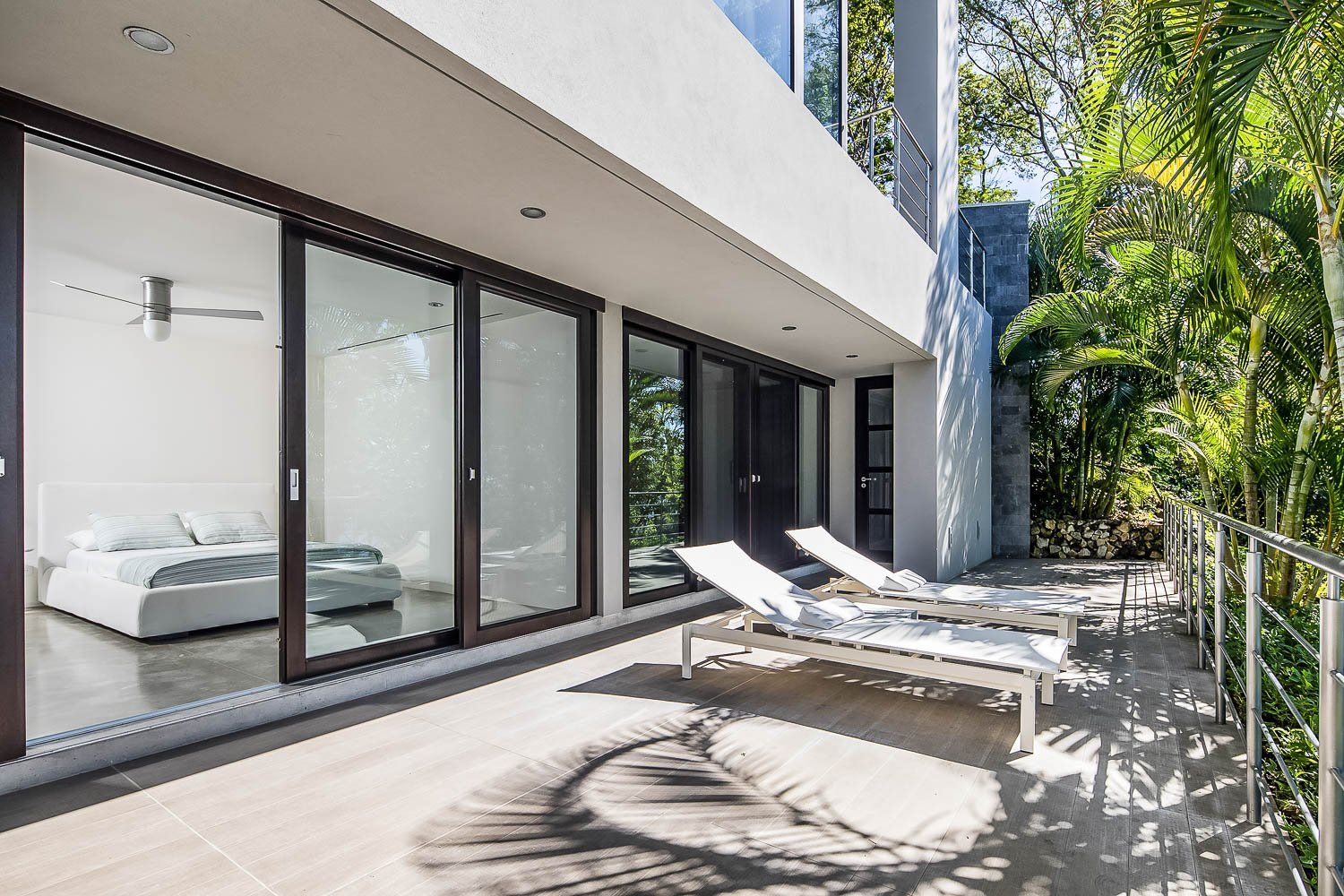 a large house with lots of windows and a balcony with lounge chairs .