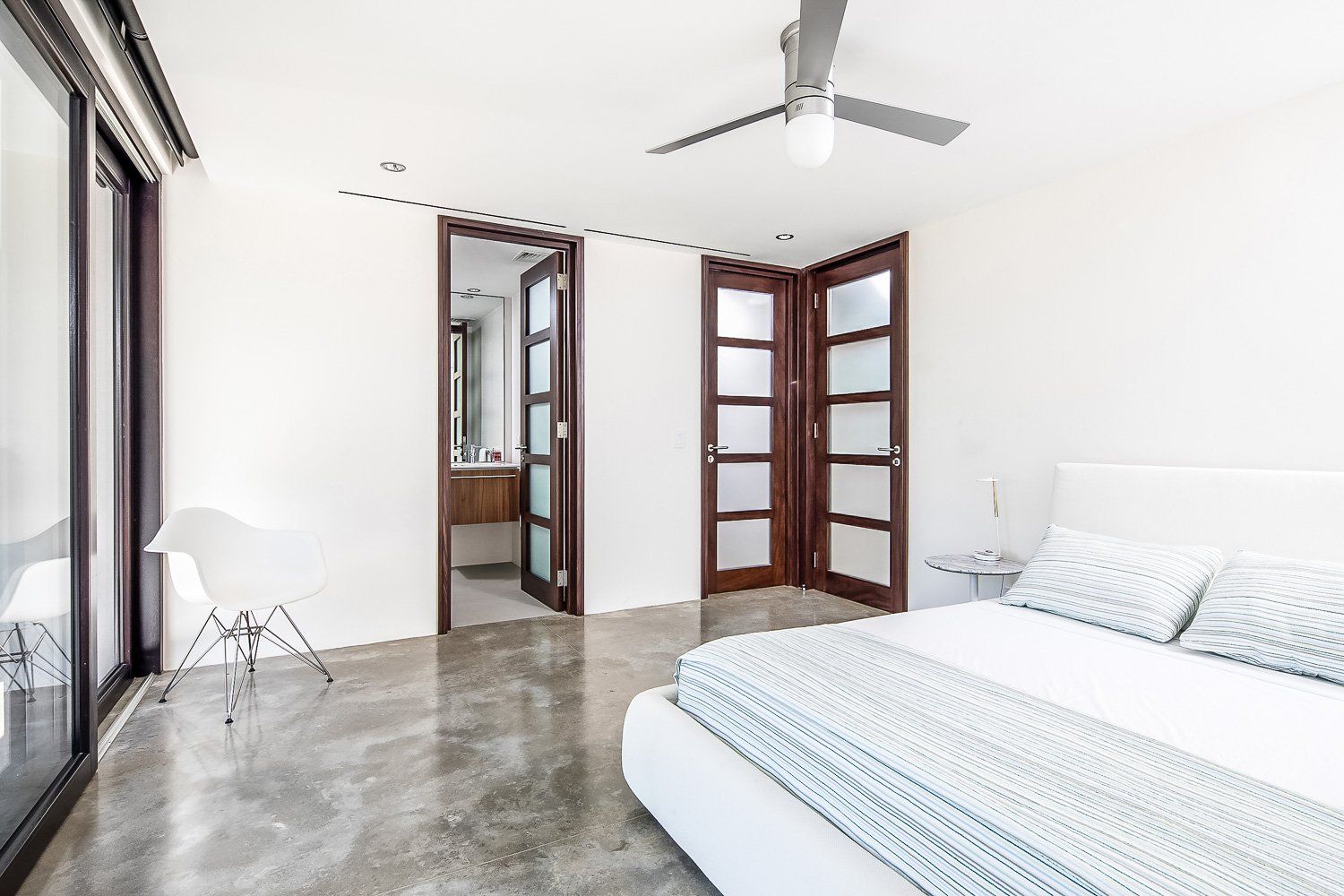 a bedroom with a bed , ceiling fan , and sliding glass doors .