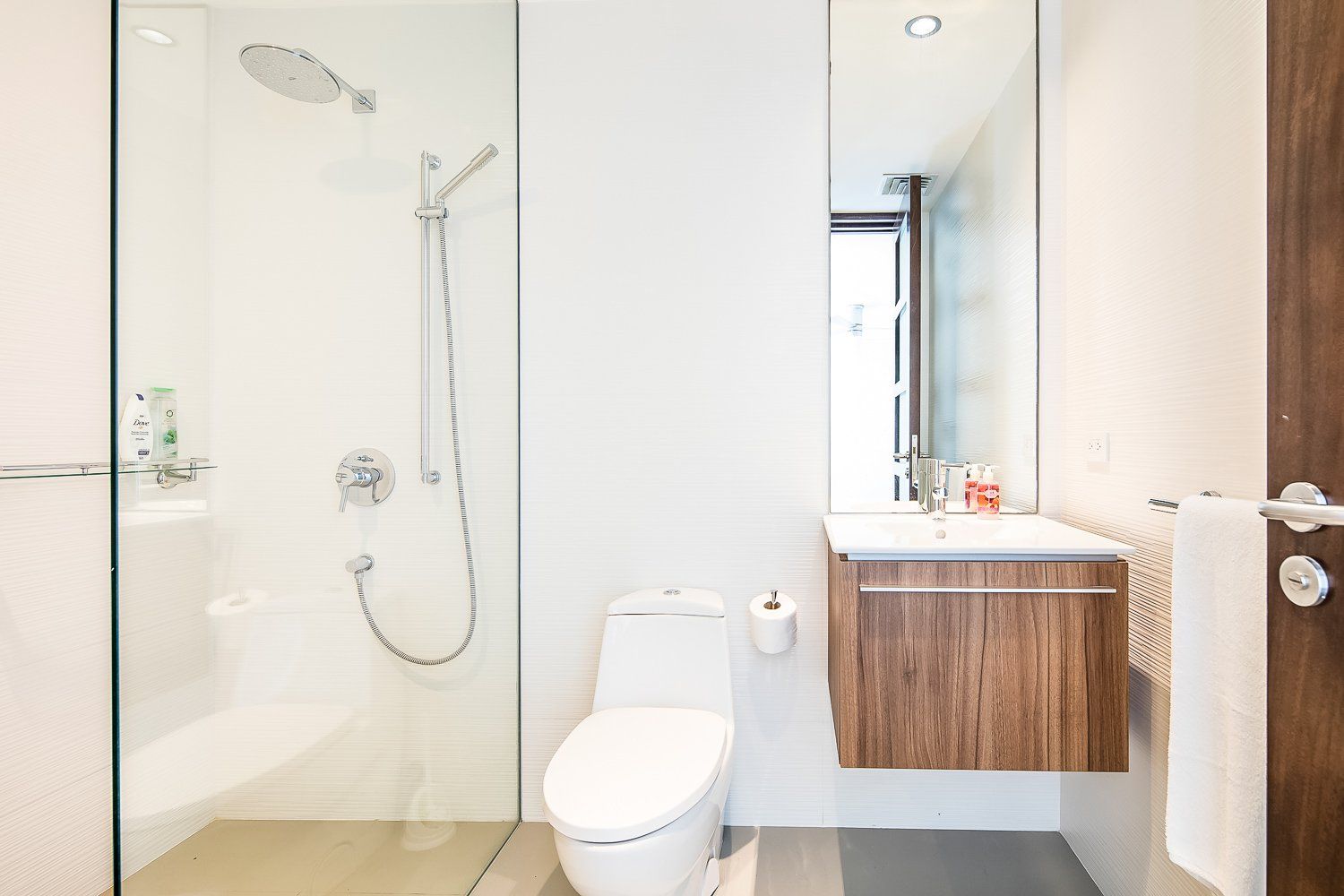 a bathroom with a toilet , sink , shower and mirror .