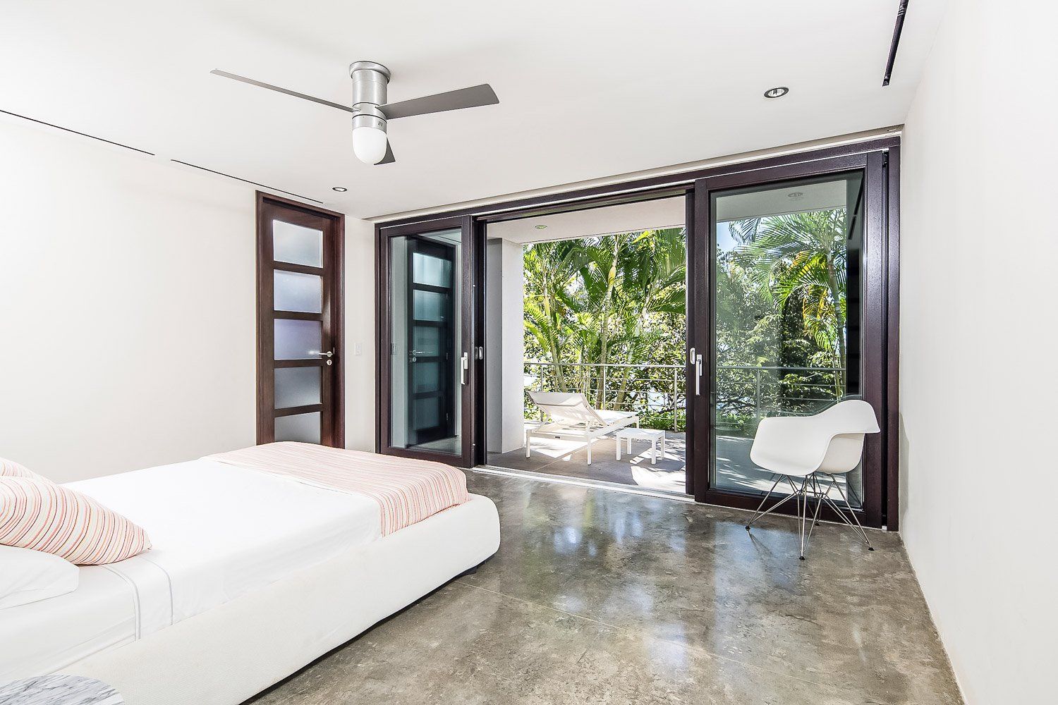 a bedroom with a bed , chair , ceiling fan and sliding glass doors .