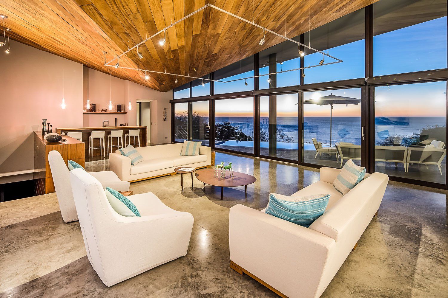 a living room with a lot of windows and a view of the ocean . Sarco