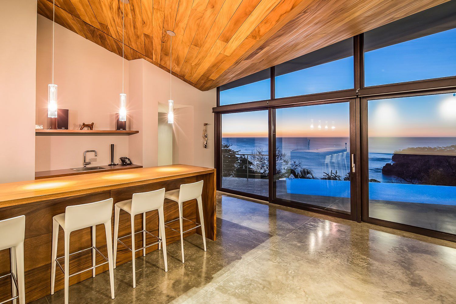 a kitchen with a bar and stools and a view of the ocean .