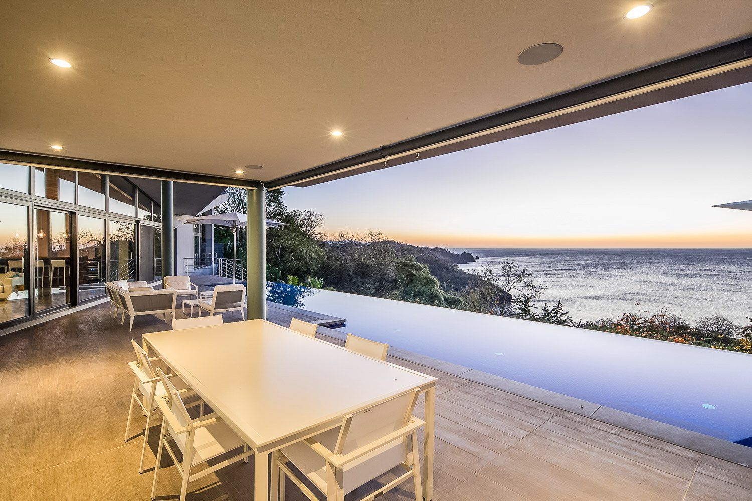 there is a table and chairs on the patio with a view of the ocean .