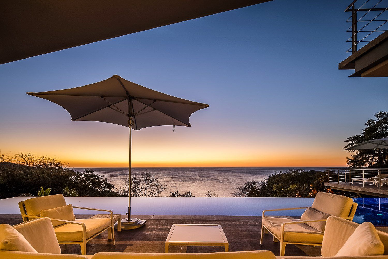 a swimming pool with a view of the ocean at sunset