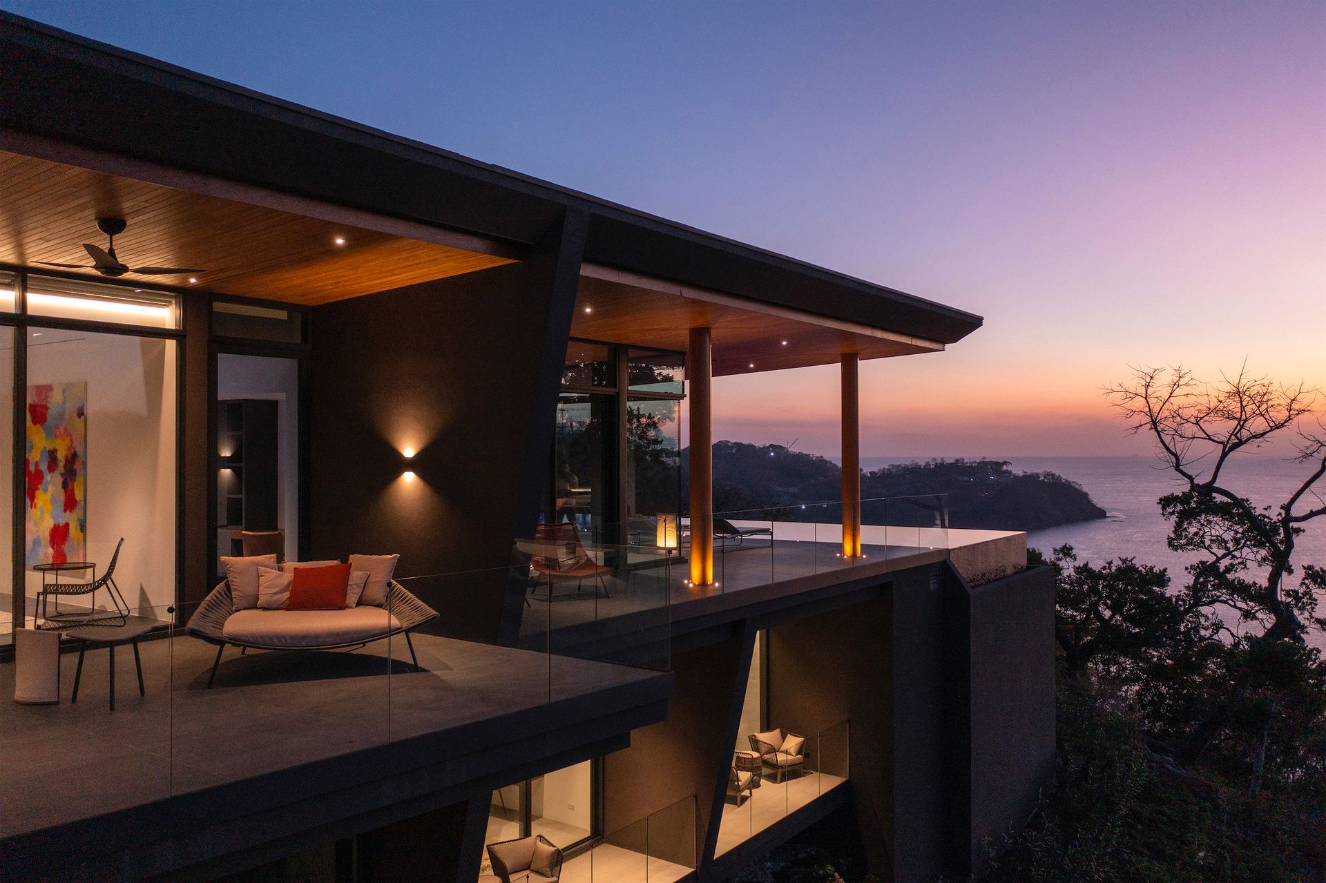 a large house with a balcony overlooking the ocean at sunset .