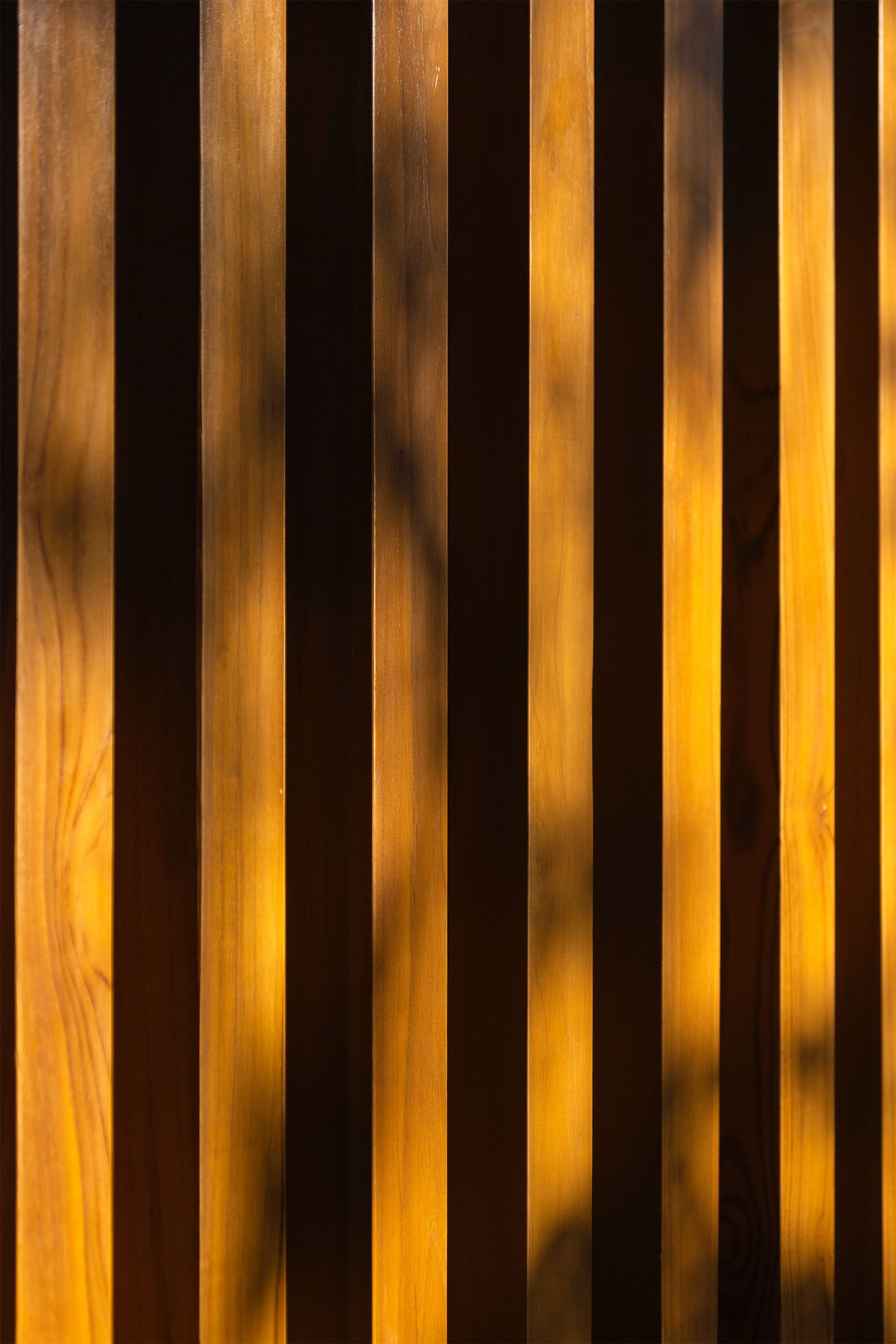 a close up of a wooden fence with a shadow of a tree on it .