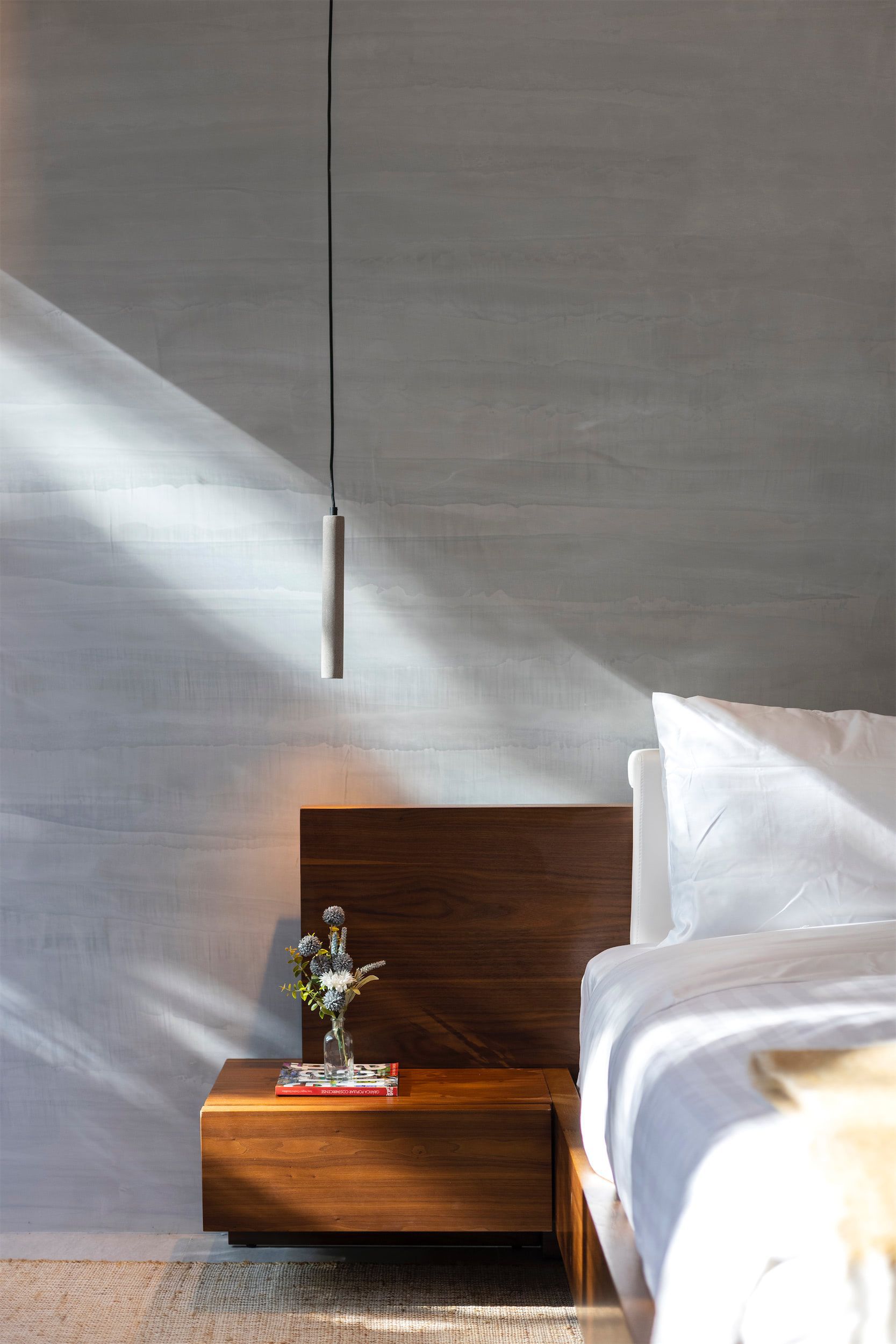 a bedroom with a bed and a nightstand with a vase of flowers on it .