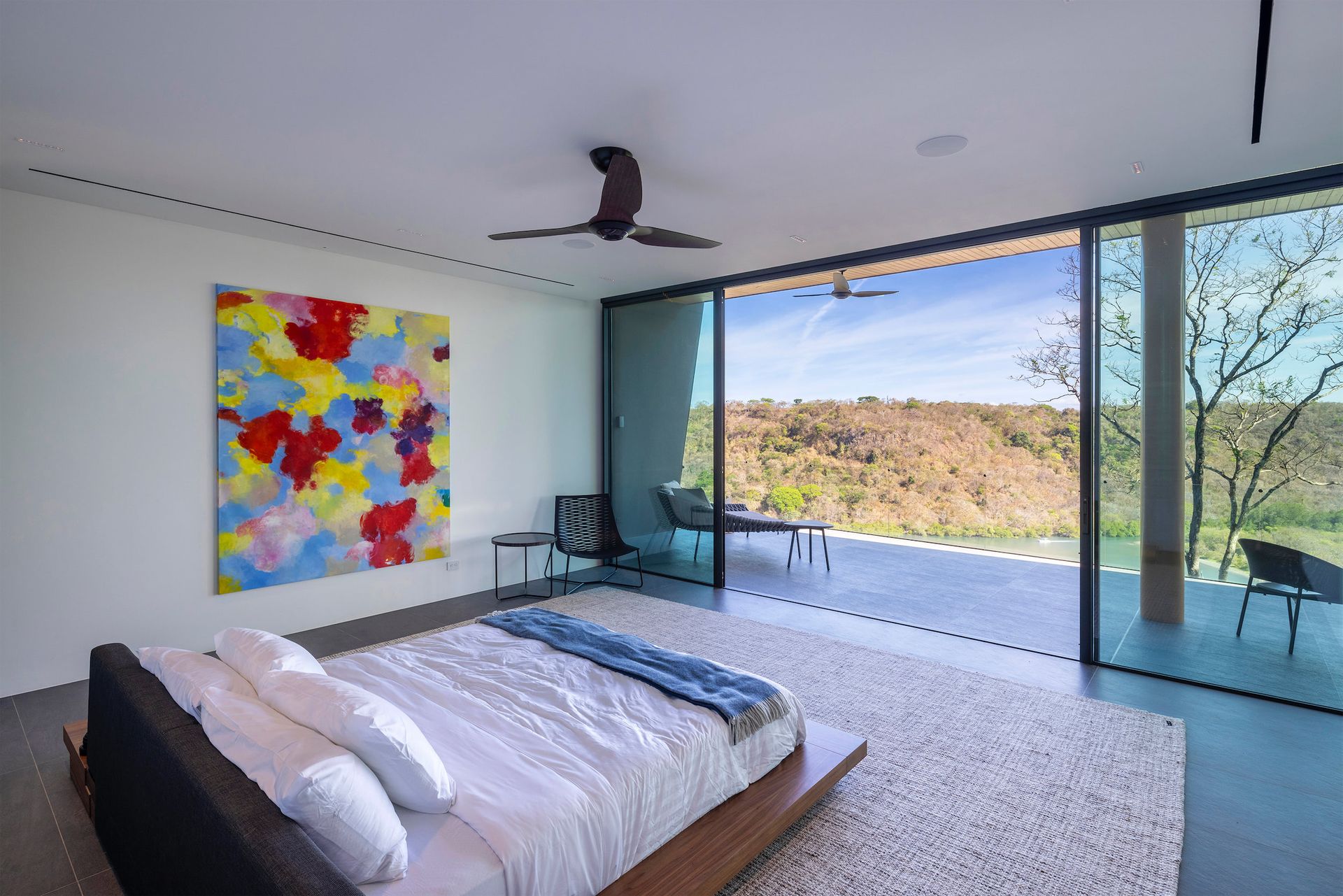 a bedroom with a large bed and a painting on the wall .