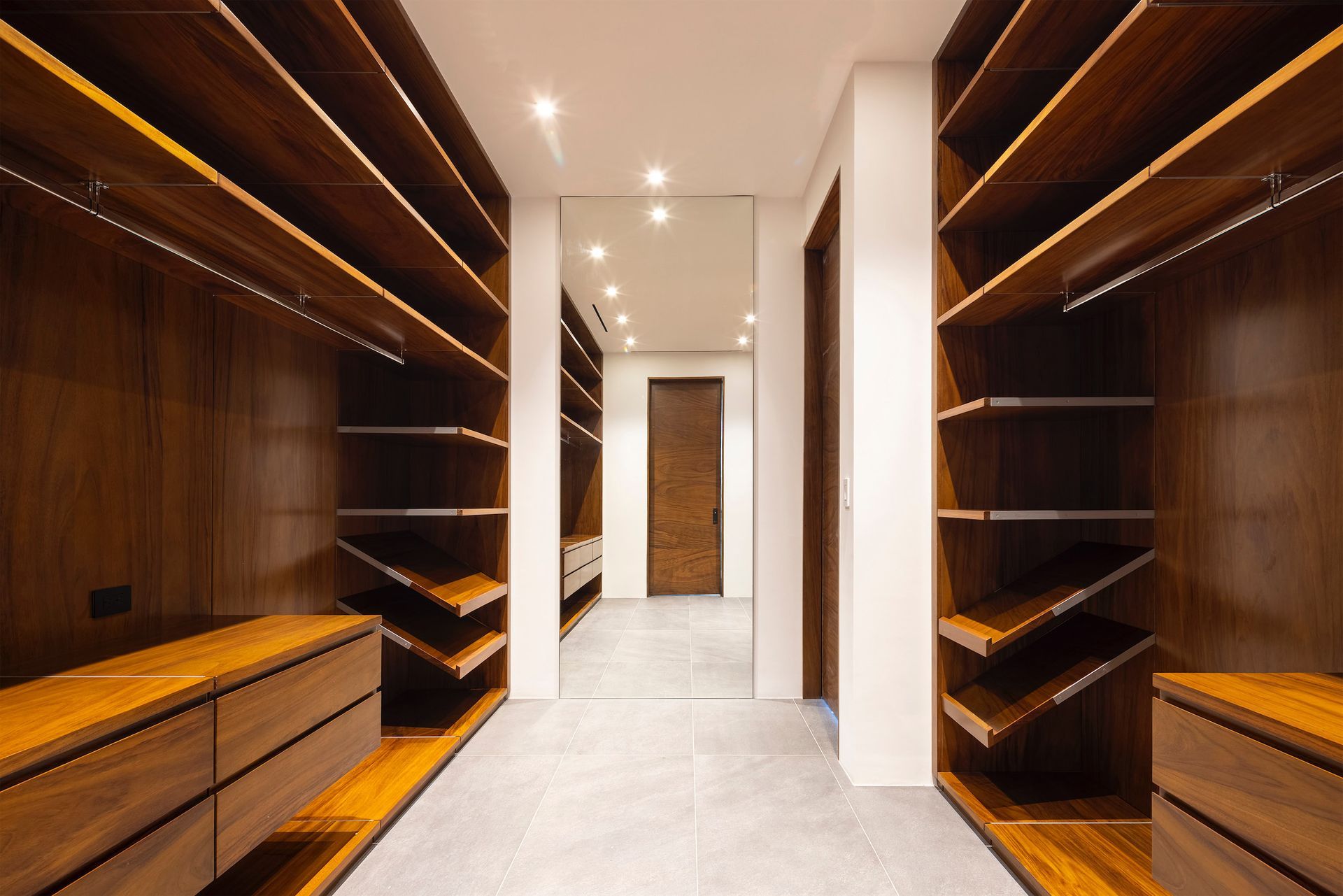 a walk in closet with wooden shelves and a mirror .