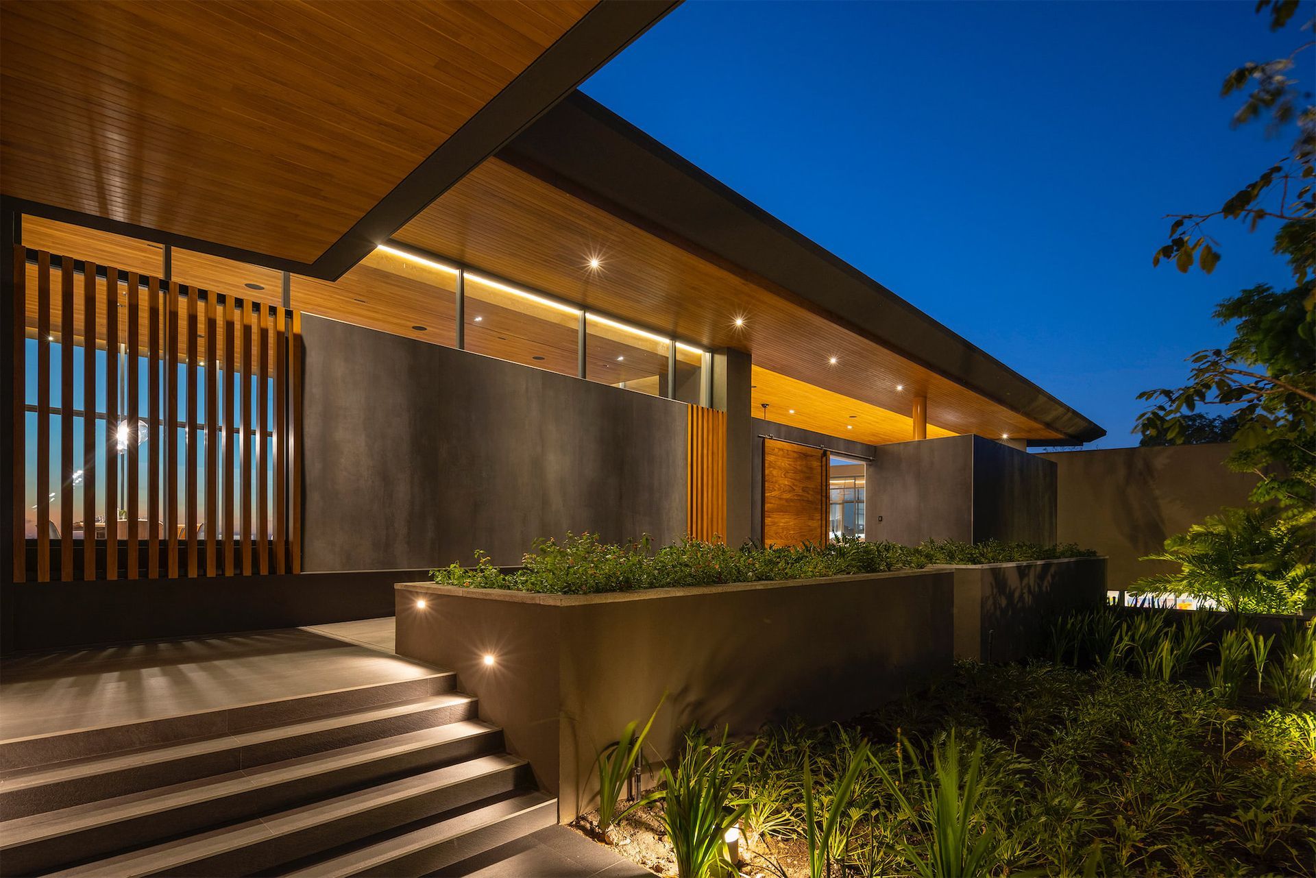 a modern house with a wooden roof and stairs at night .