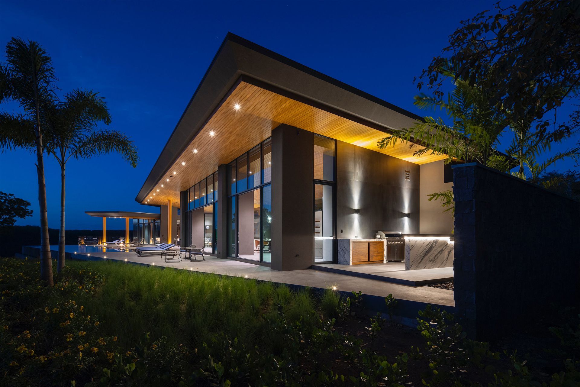 a modern house with a large roof is lit up at night .