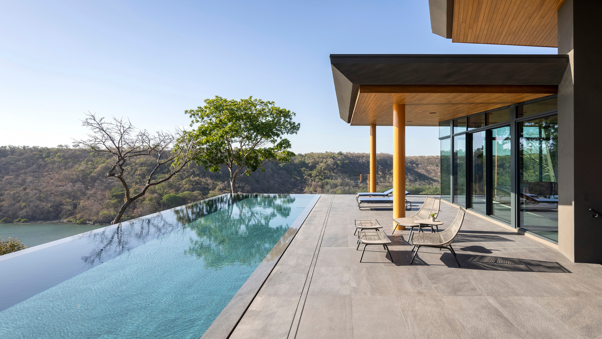 A private jet is flying over an infinity pool in front of a luxury house by Sarco Architects
