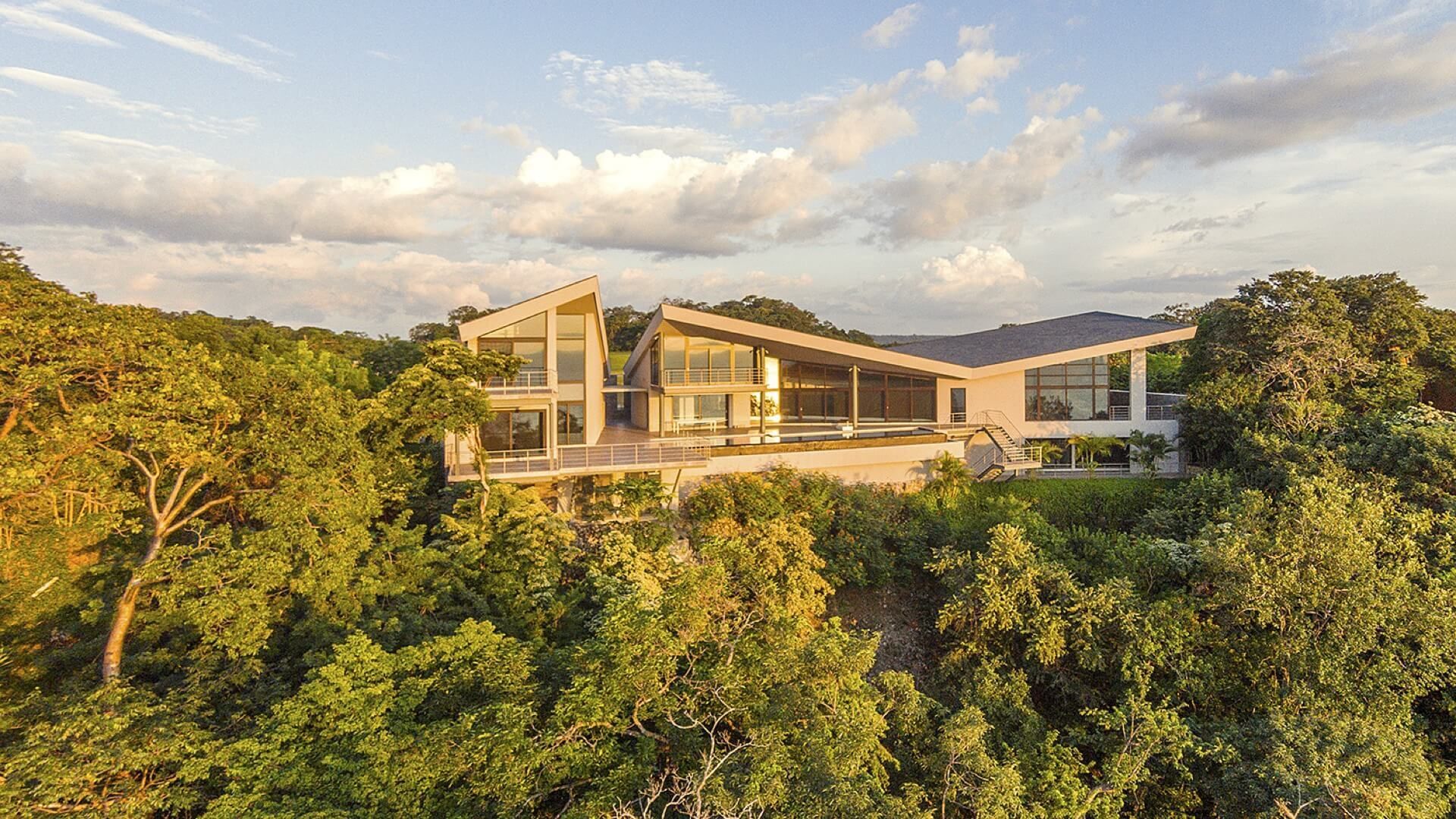 An aerial view of a large house in the tropics surrounded by trees. maximize views in luxury home