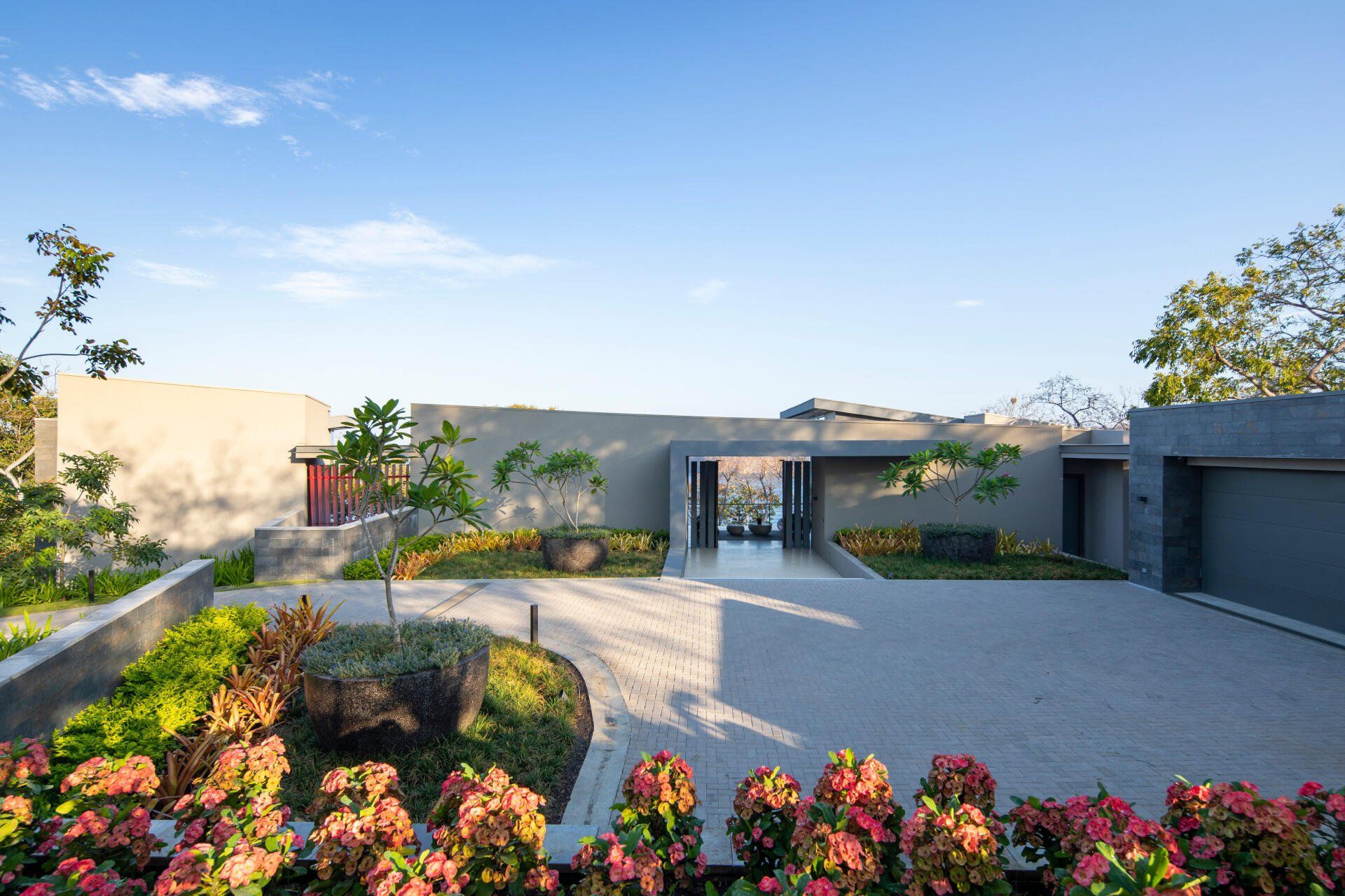 a modern house with a large driveway and flowers in front of it .