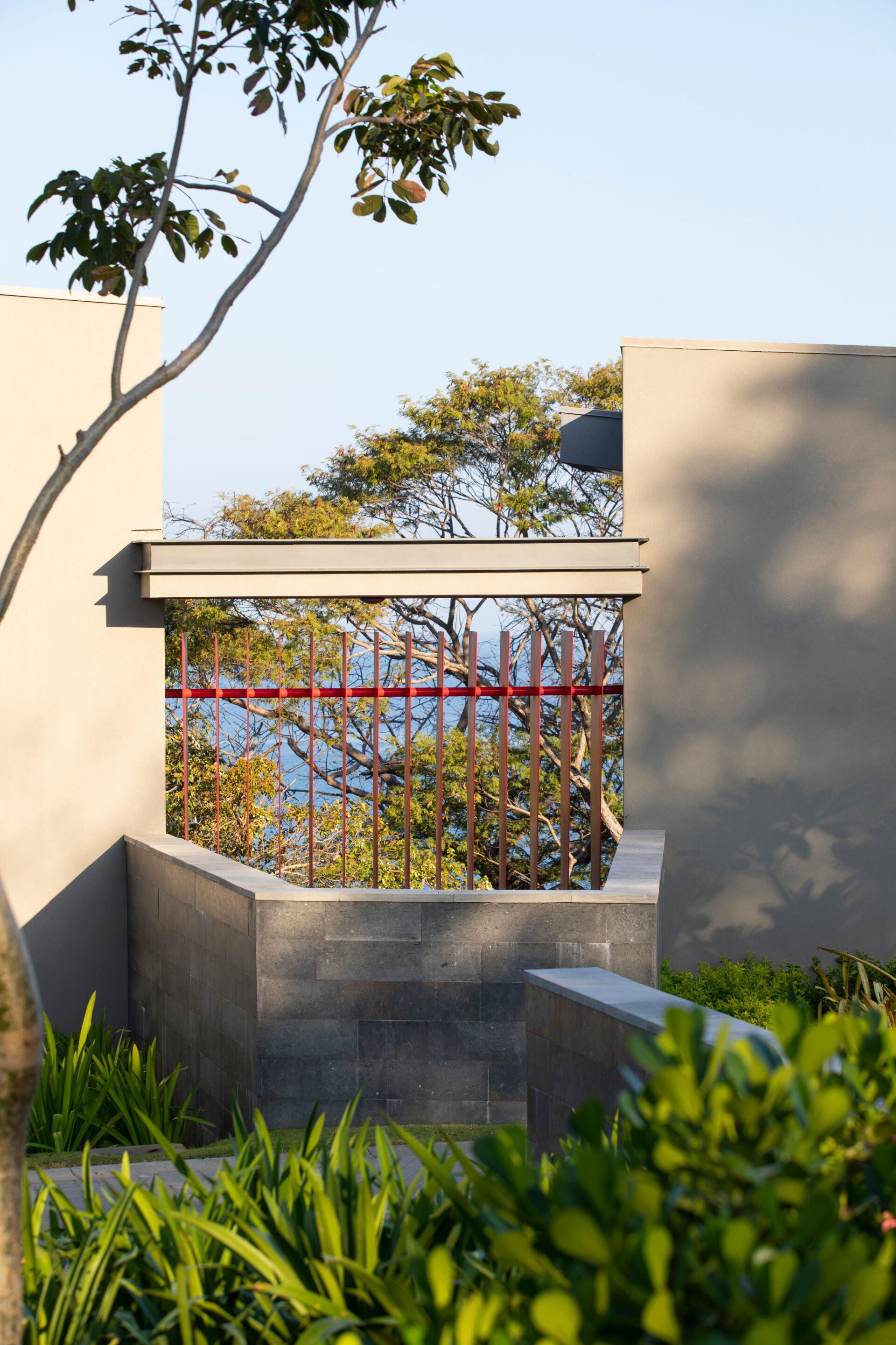 a fence with a tree in the foreground and a view of the ocean in the background .