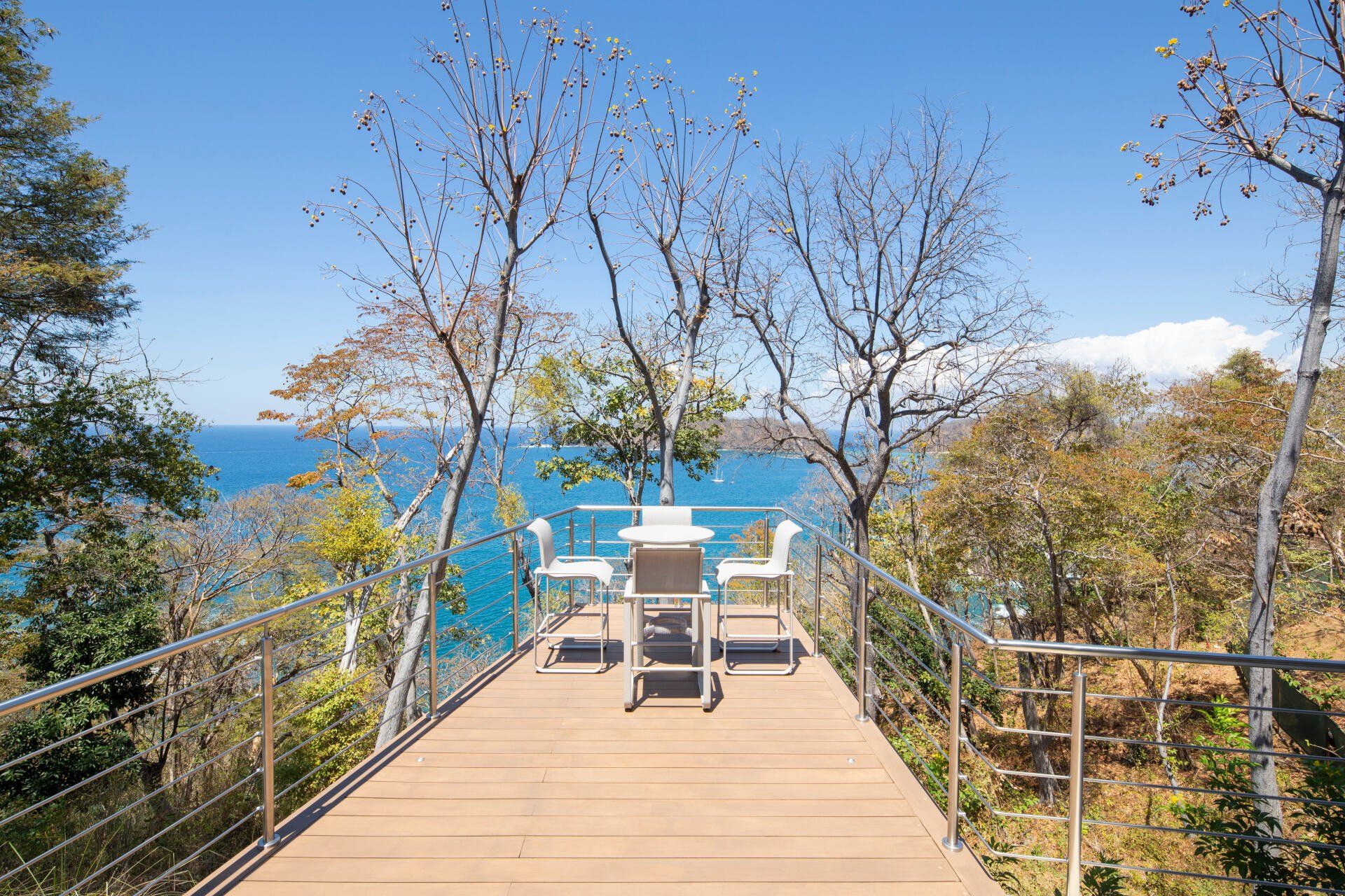 a wooden deck with a table and chairs overlooking the ocean .