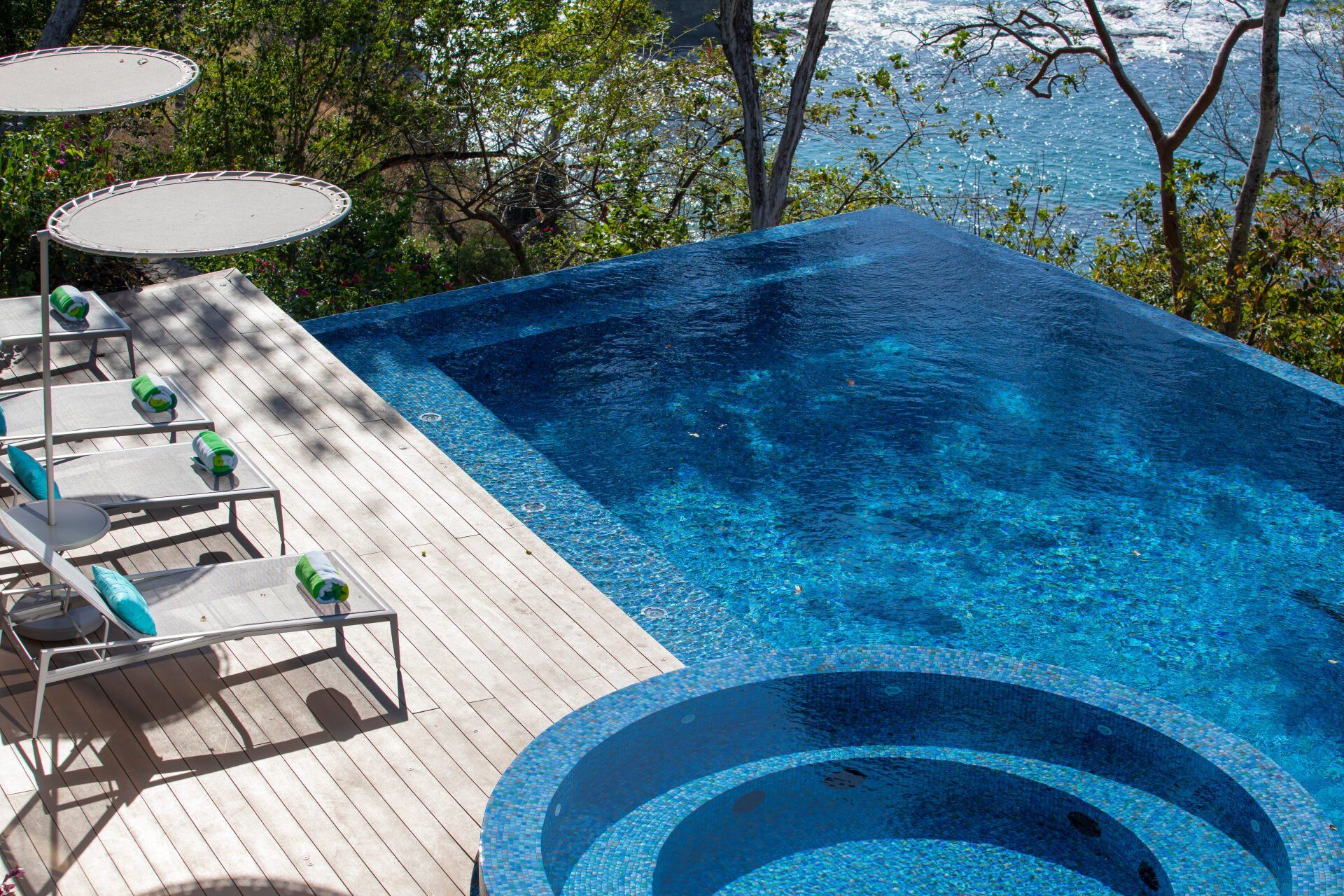 a large swimming pool surrounded by chairs and umbrellas next to the ocean .
