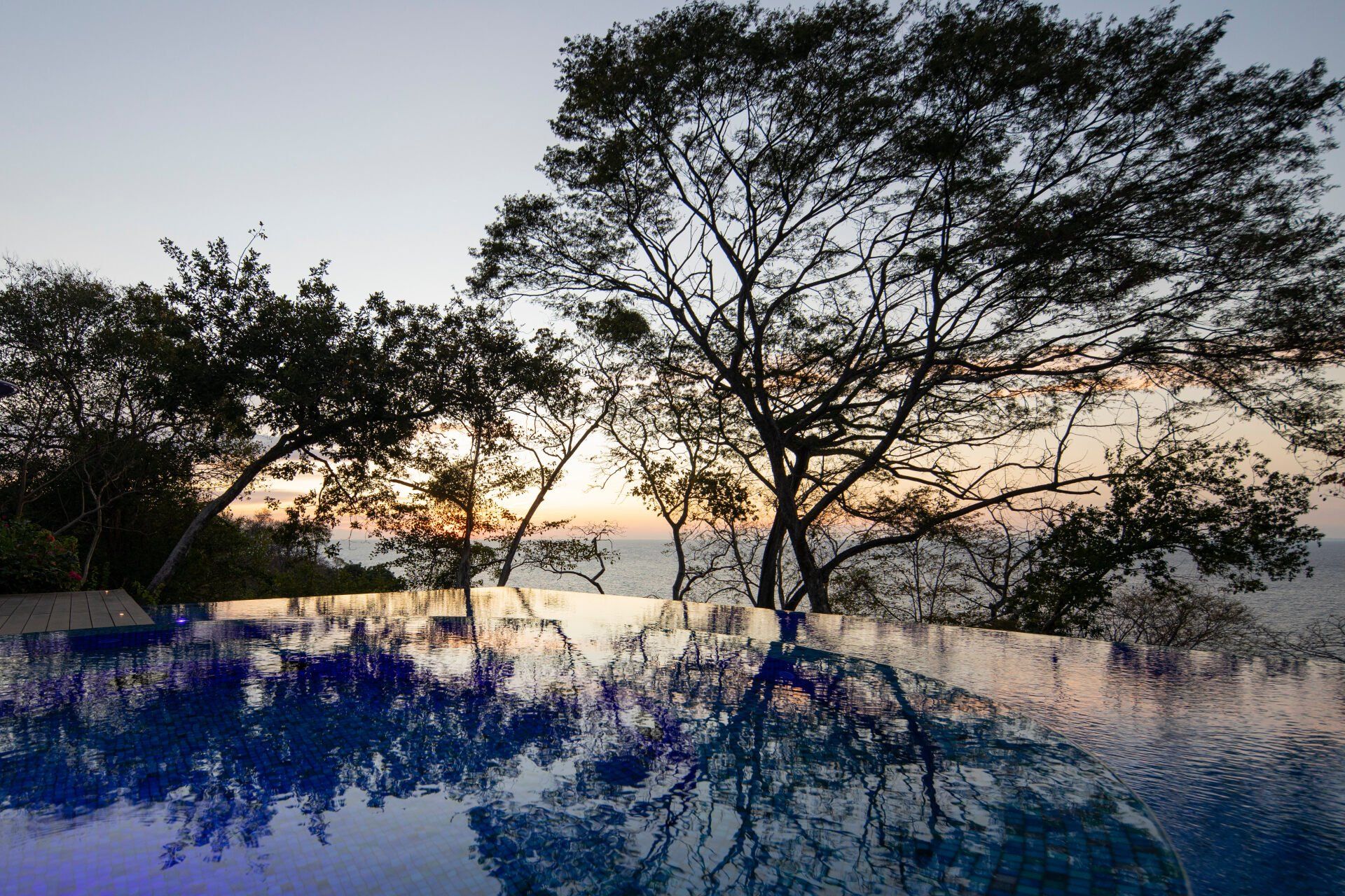 a swimming pool with trees in the background at sunset