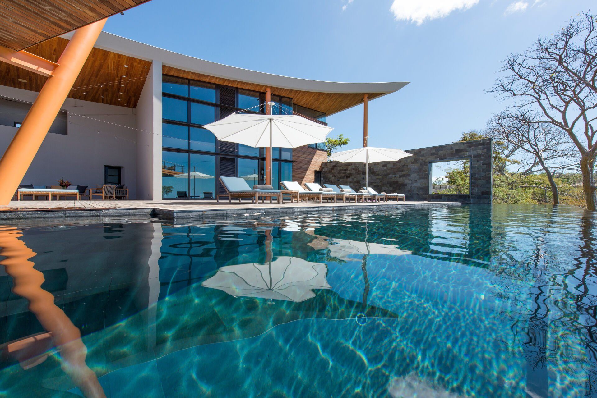 a large swimming pool with umbrellas in front of a house