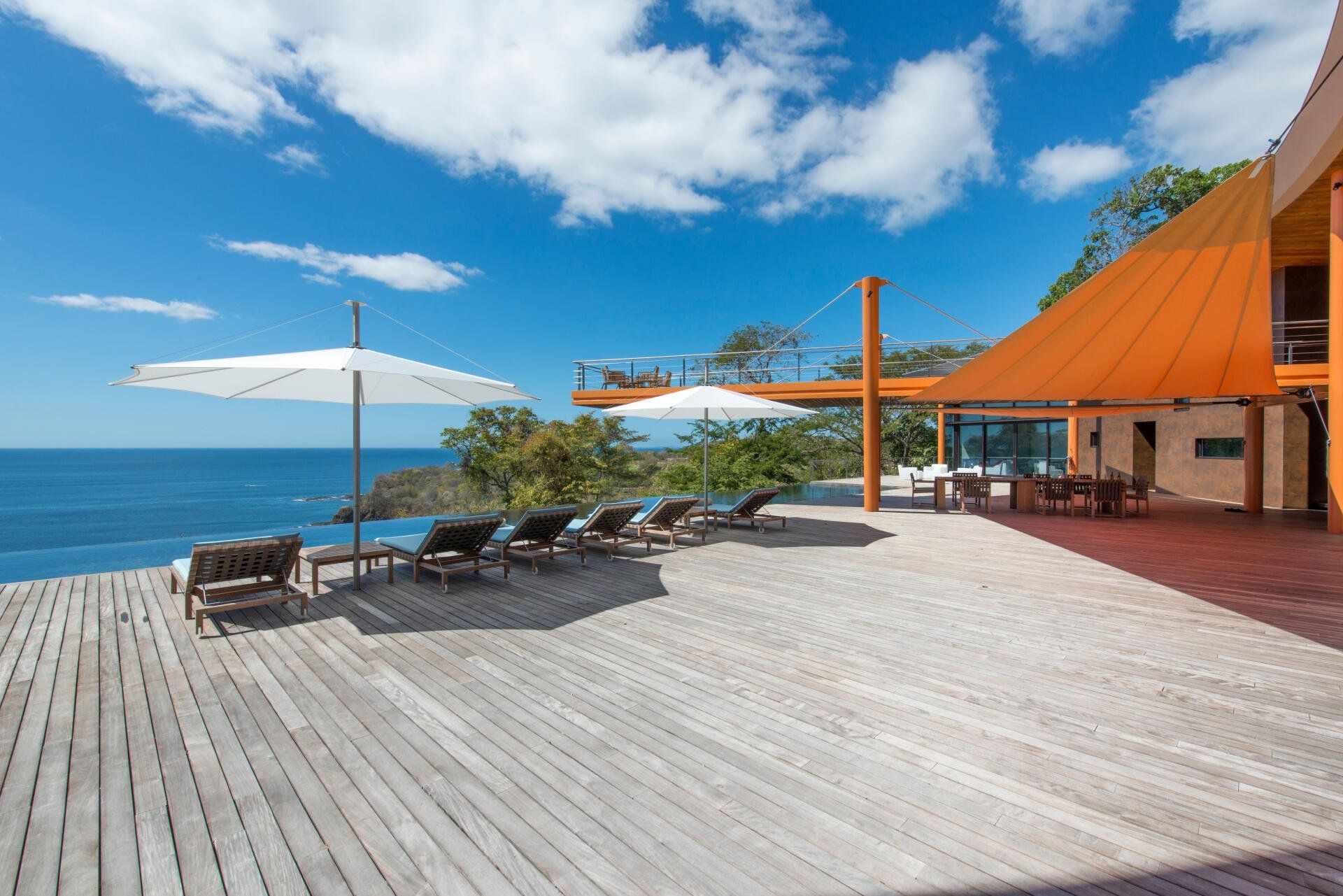 a deck with chairs and umbrellas overlooking the ocean