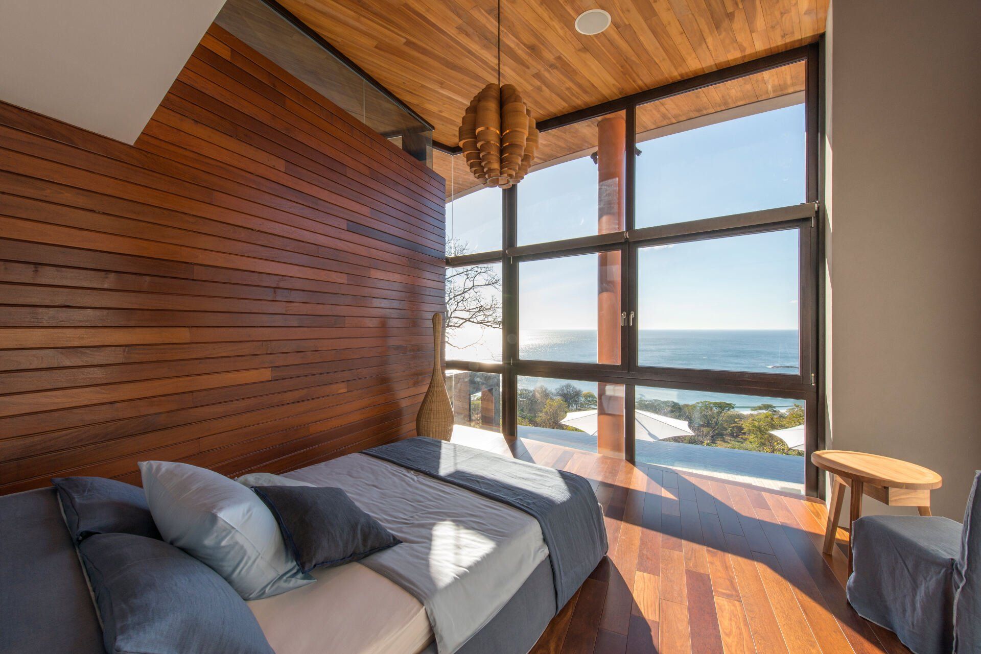 a bedroom with a large bed and lots of windows overlooking the ocean .