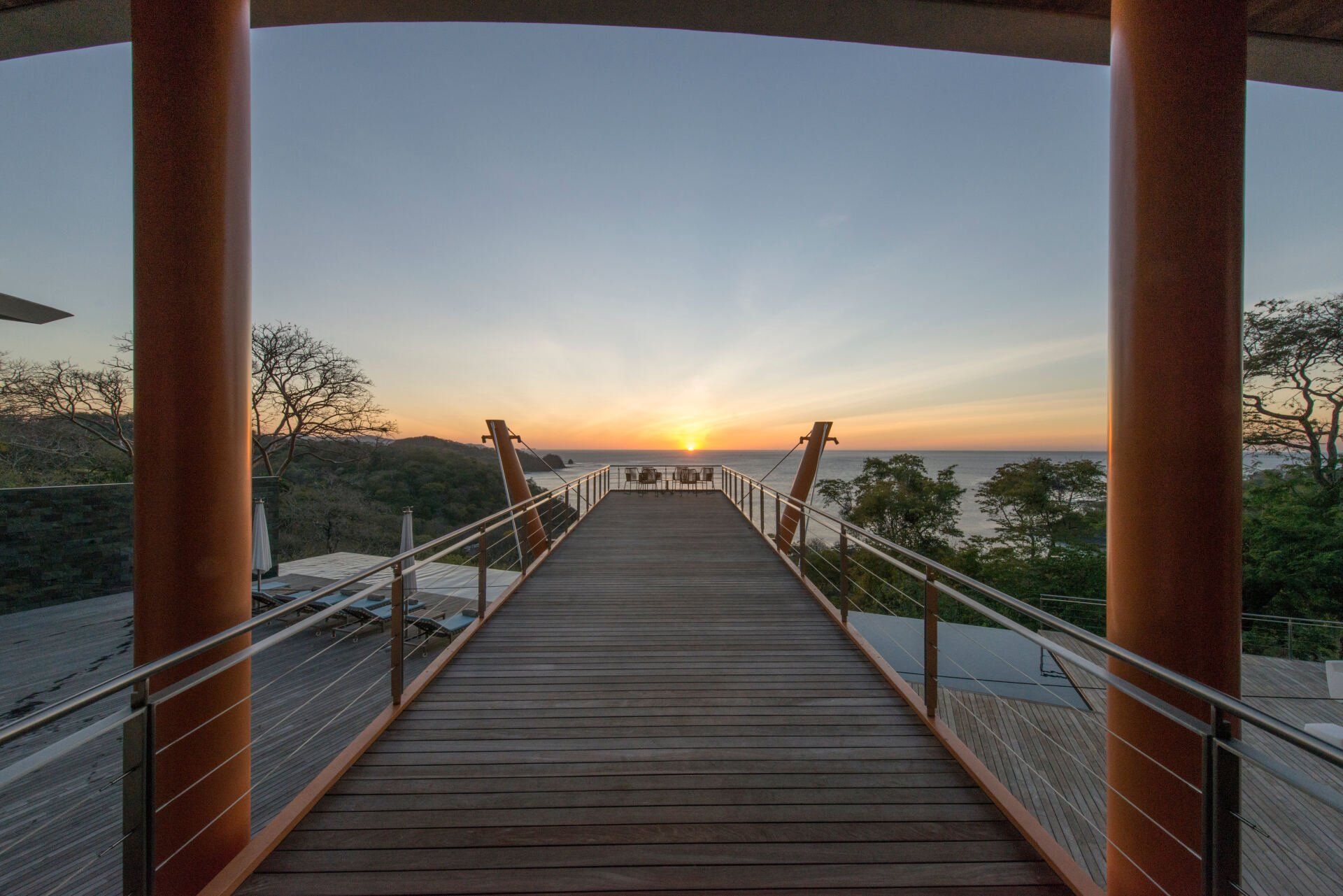 a wooden walkway leading to the ocean at sunset