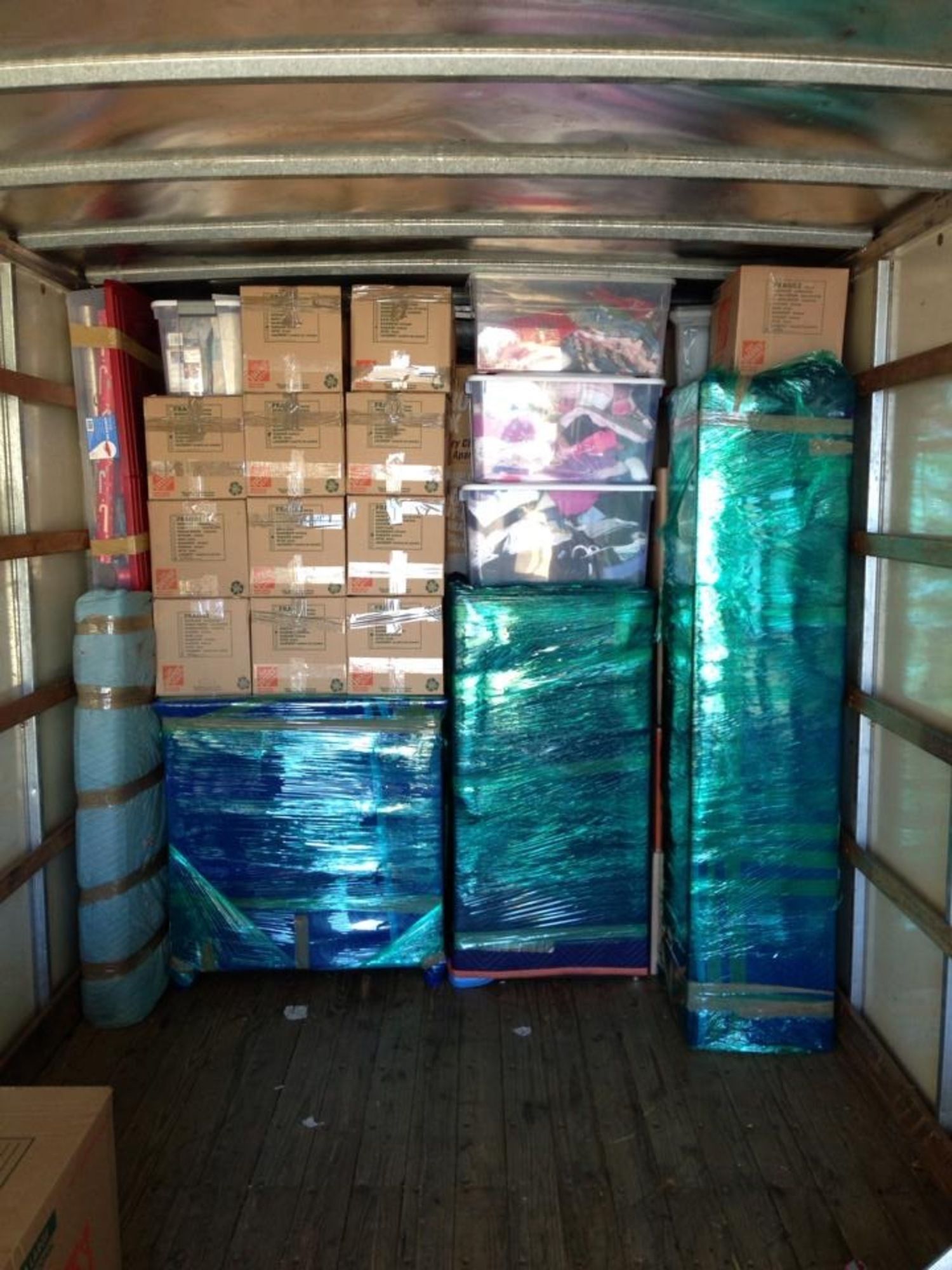 The inside of a moving truck filled with boxes and plastic wrap