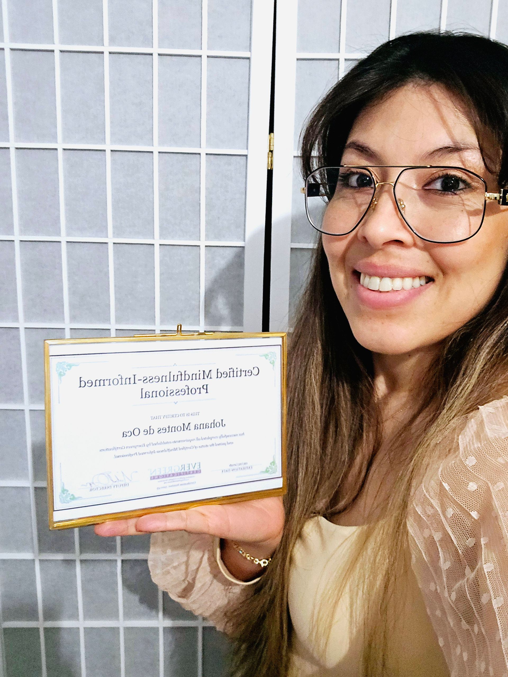 A woman wearing glasses is holding a certificate in her hand.