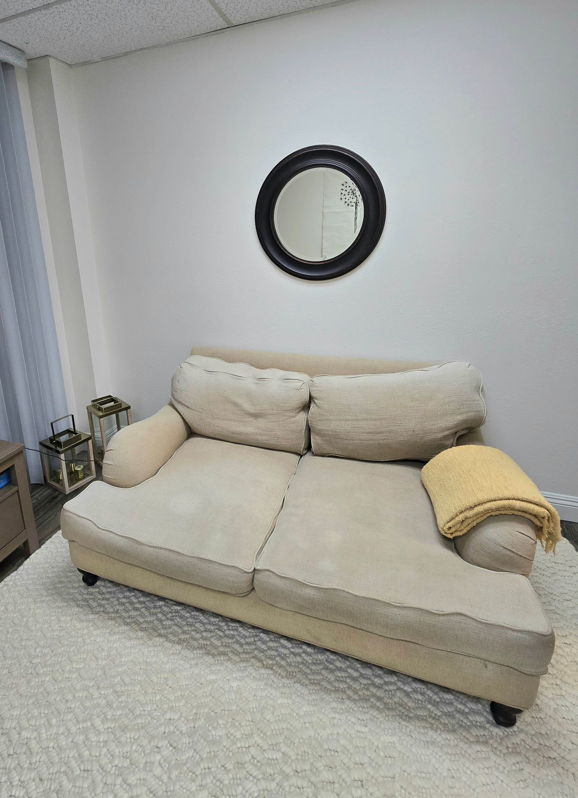 A living room with a couch and a mirror on the wall.