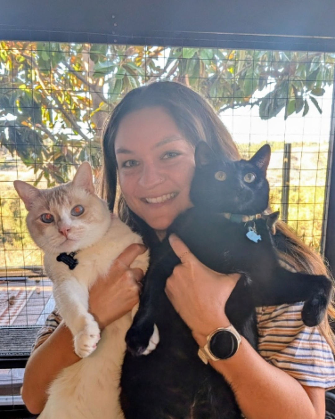 Woman smiling at a table, eating a burger and chips in a restaurant, wearing a sweater.