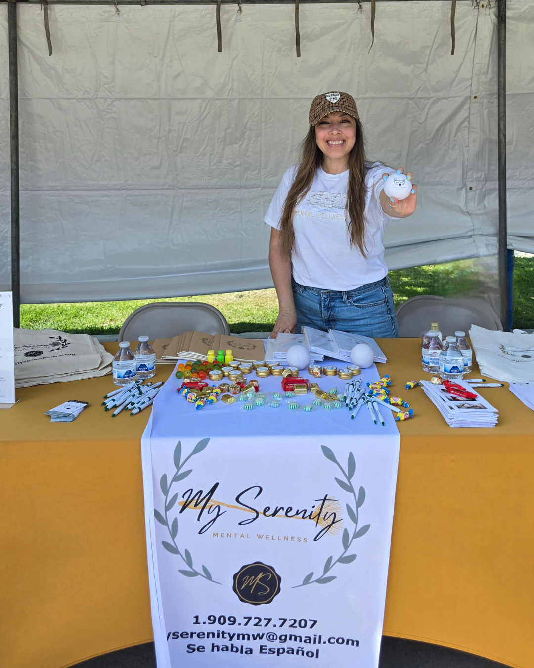 Woman smiling at a table, eating a burger and chips in a restaurant, wearing a sweater.