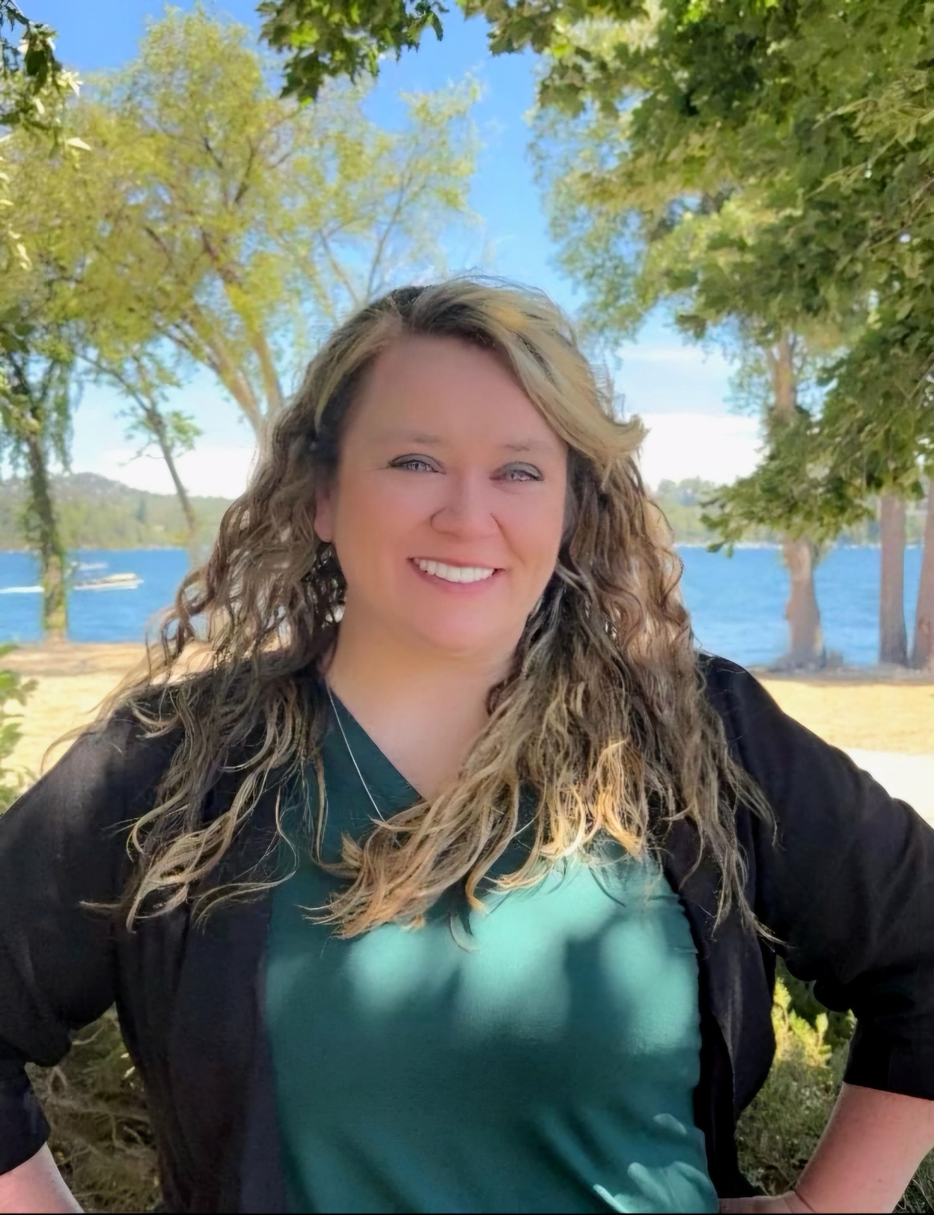 A woman is standing in front of a tree with her hands on her hips.