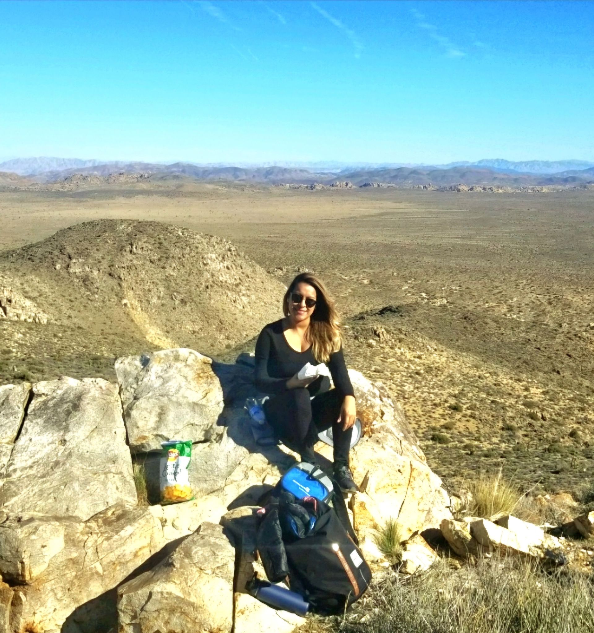 A woman is sitting on a rock in the desert